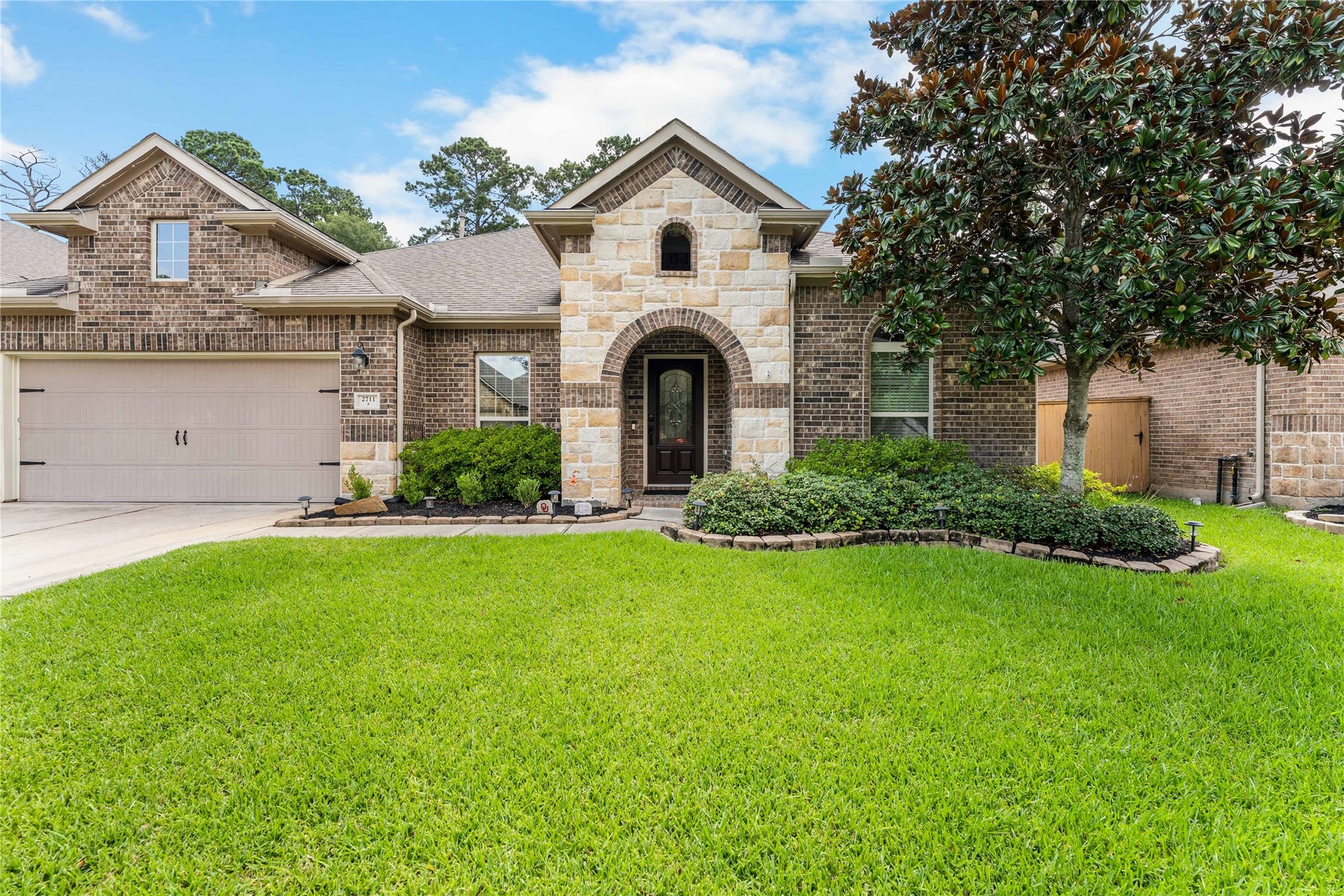 Front elevation showcasing timeless brick and stone architecture with manicured landscaping in Graystone Hills.