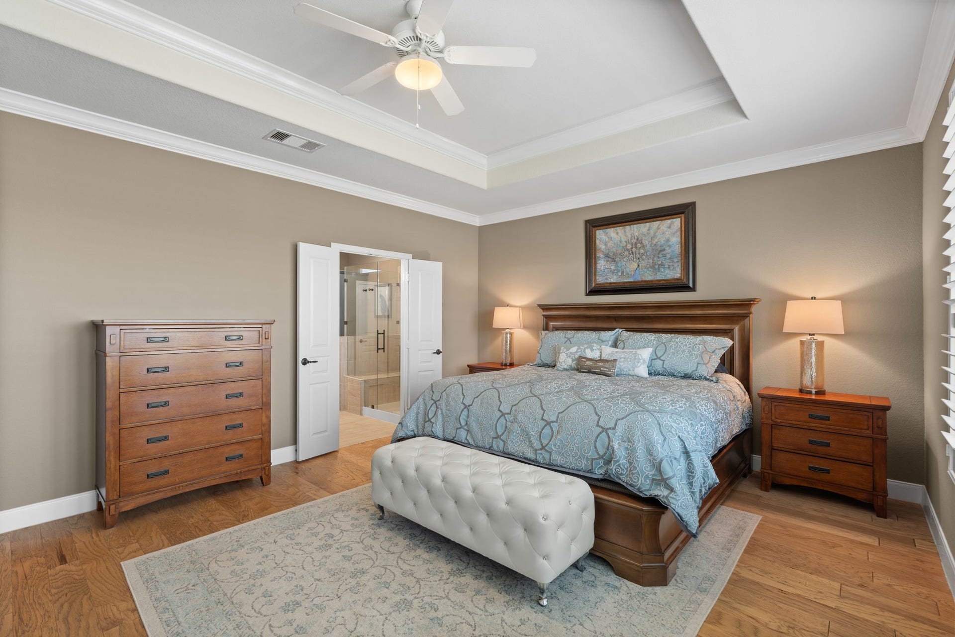 View from the owners suite into the spacious primary bath, offering a seamless transition between private and relaxing spaces. The Tray ceiling and double crown molding adds an elegant touch, and the two-tone paint makes the room warm and inviting.
