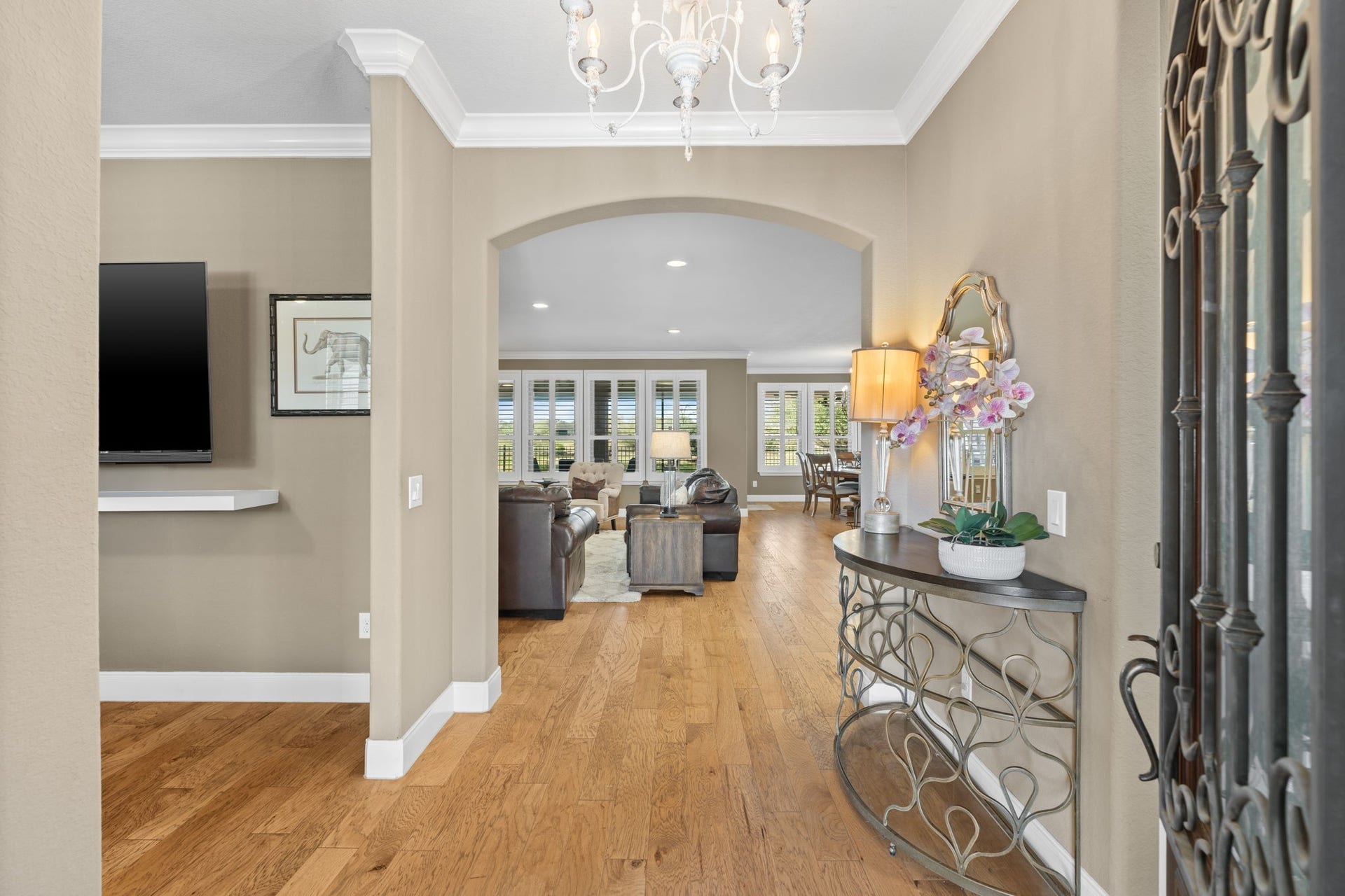 Captivating entryway showcasing elegant crown molding and 5 1/4" baseboards for a refined touch and a distressed white French chandelier.