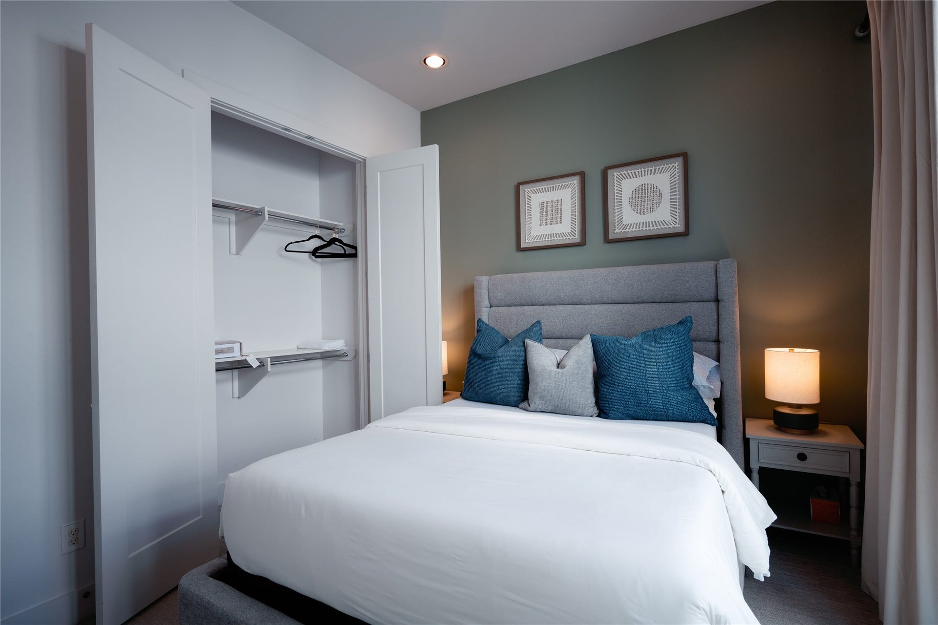 2826 Clay Street, Houston, TX 77003 Cozy bedroom with a stylish upholstered bed, accented by blue and gray pillows. A small nightstand with a lamp offers a warm touch, while the open closet provides convenient storage space.