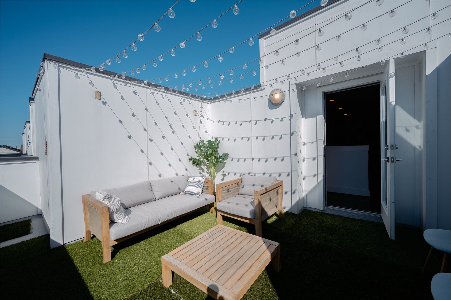 2826 Clay Street, Houston, TX 77003 Charming rooftop patio featuring cozy seating, lush artificial grass, and string lights for perfect outdoor relaxation.
