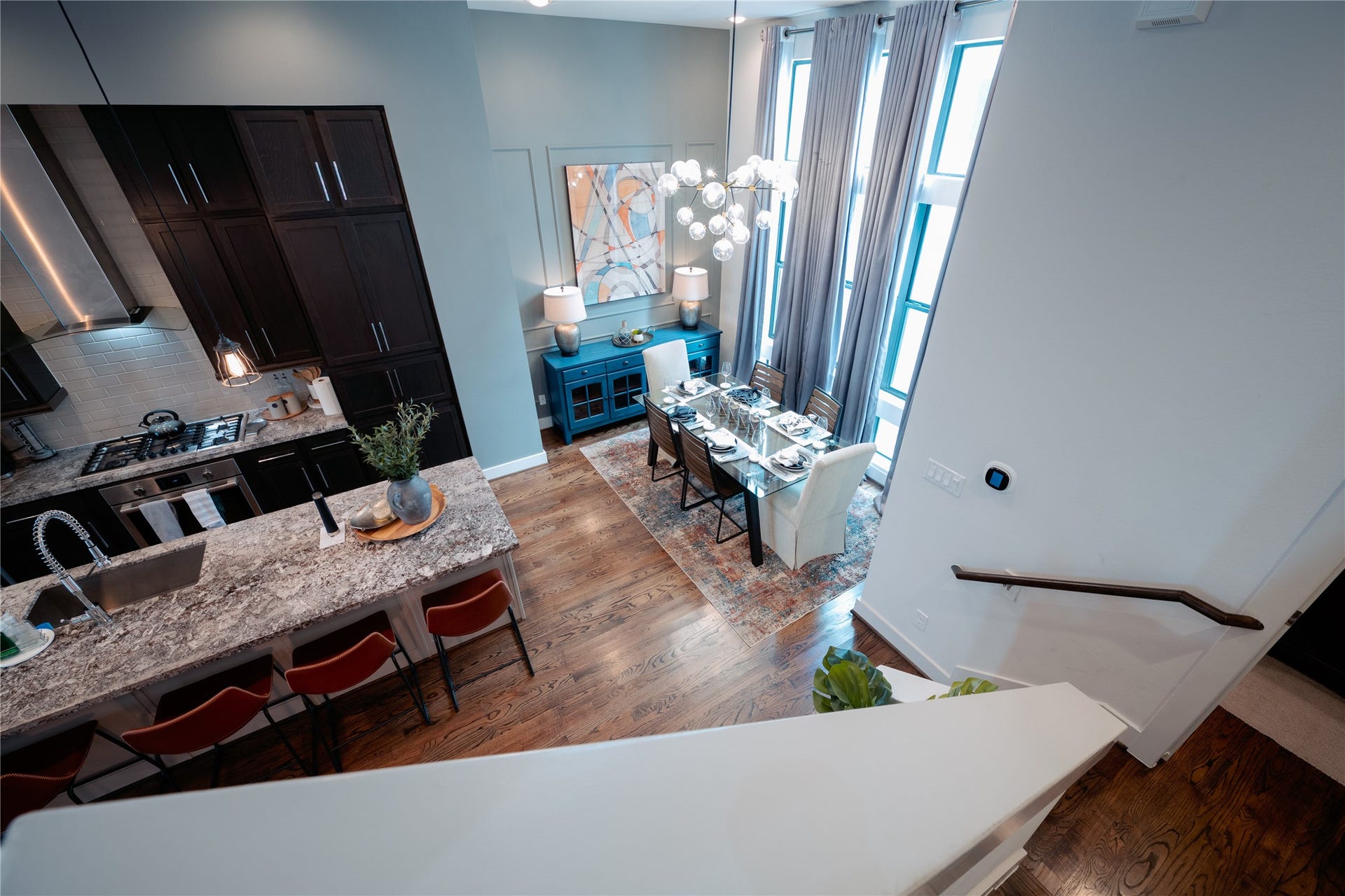 2826 Clay Street, Houston, TX 77003 Elegant open-concept kitchen and dining area featuring high ceilings, a modern chandelier, and large windows that flood the space with natural light. The kitchen boasts dark cabinetry, a granite countertop, and a stylish backsplash.
