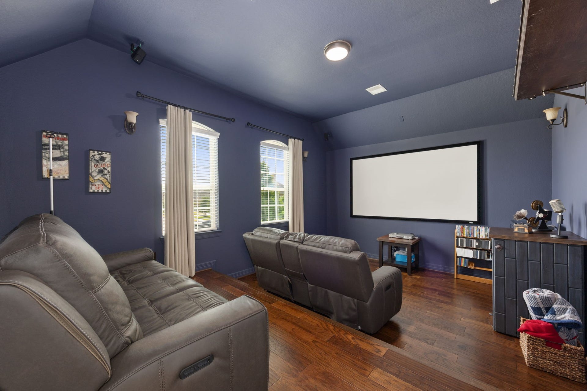 13522 Columbia Key Drive, Tomball, TX 77377 A dedicated media room with rich dark blue walls, tiered seating, and a large projector screen creates the perfect setting for movie nights, game days, or immersive entertainment.