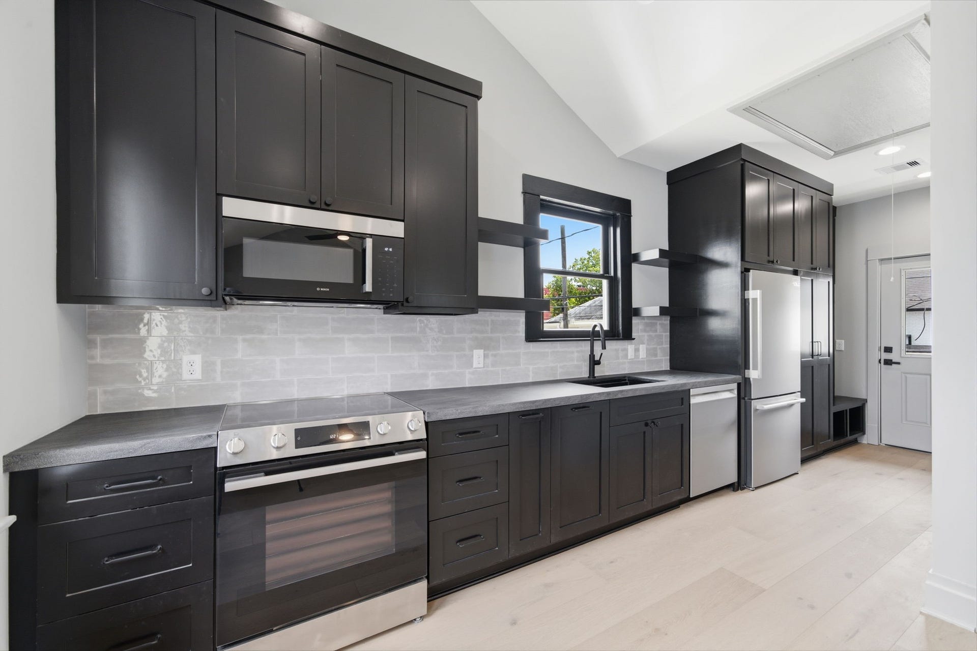 404 Avondale Street, Houston, TX 77006 The APARTMENT: Custom kitchen featuring classic black cabinetry, stainless steel appliances complemented by ample natural light.