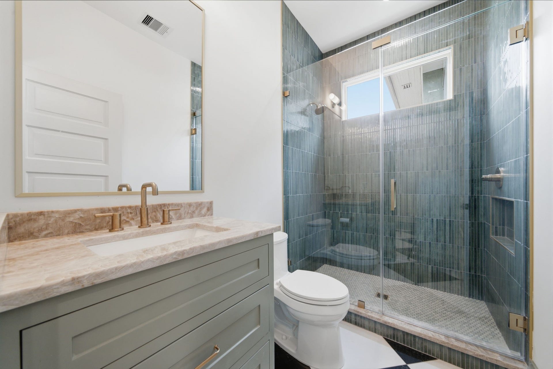 404 Avondale Street, Houston, TX 77006 Downstairs full bathroom featuring a glass-enclosed shower, stylish vanity with a quartz countertop, and sleek Delta brushed gold fixtures.
