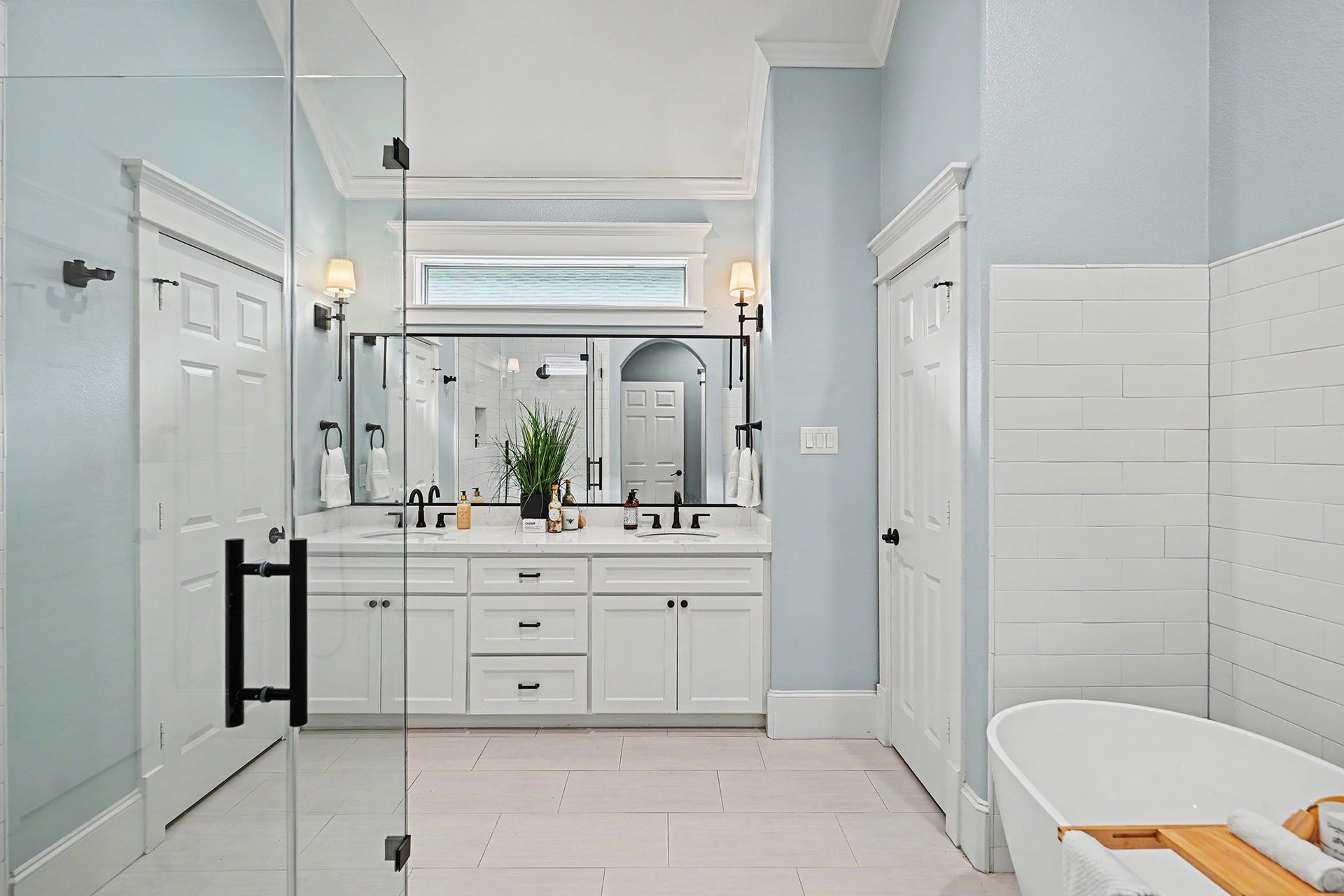 Elegant primary bathroom is well-appointed with quartz counter, double sinks, frameless walk-in shower and freestanding tub.