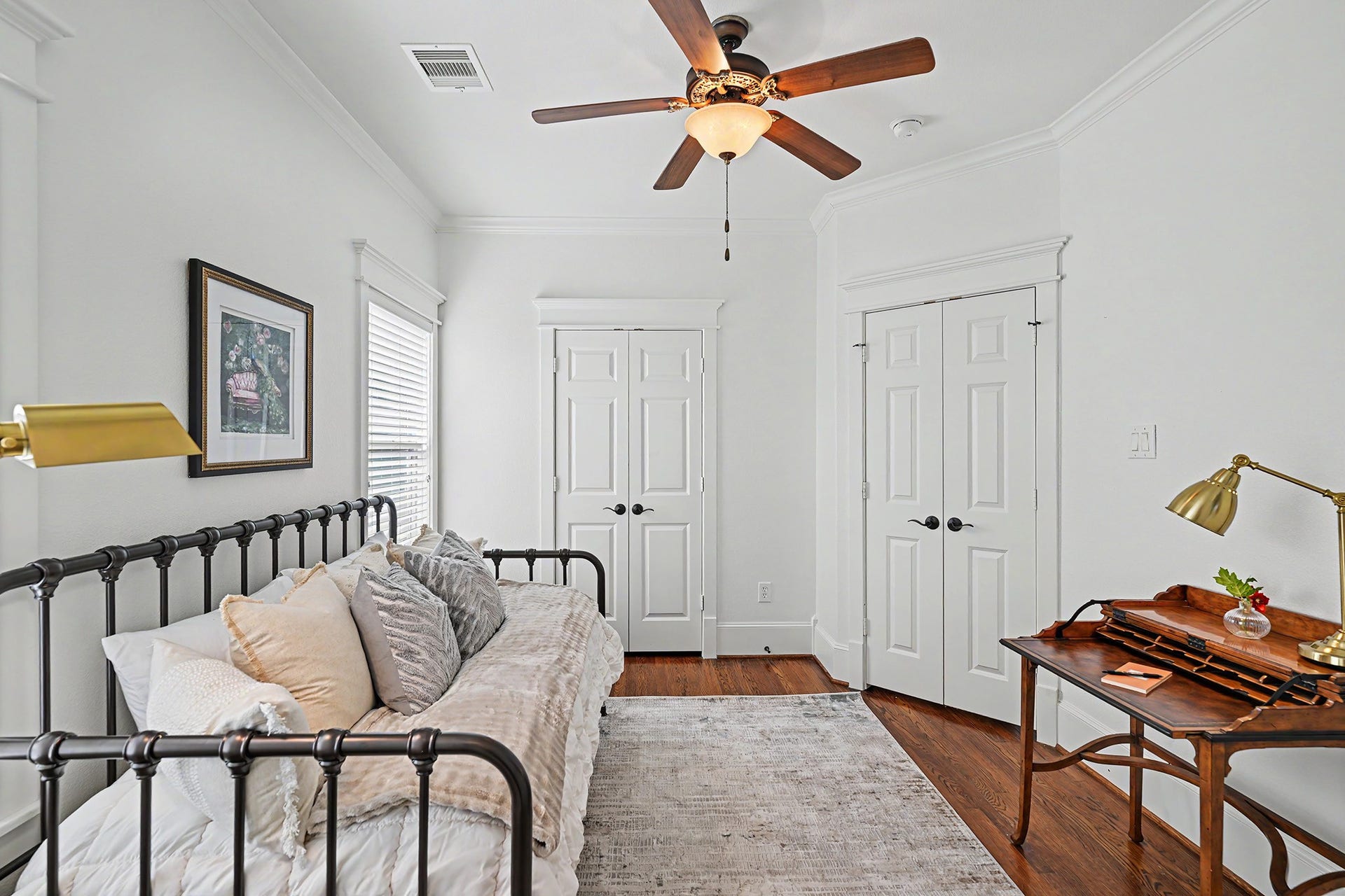 Third bedroom with ceiling fan, window treatments and hardwood floors.