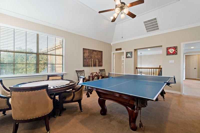 22 Waters Lake Boulevard, Missouri City, TX 77459 Spacious game room featuring a ping pong table and a card table, enhanced by natural light and a ceiling fan for comfort.