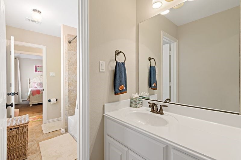 22 Waters Lake Boulevard, Missouri City, TX 77459 Bright bathroom with a large mirror, elegant fixtures, and convenient access to an adjacent bedroom.