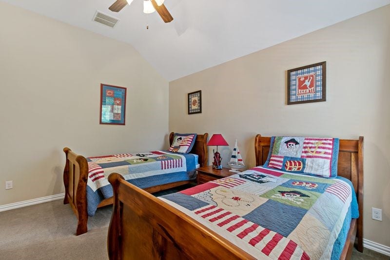 22 Waters Lake Boulevard, Missouri City, TX 77459 Charming bedroom with twin wooden beds featuring colorful patchwork quilts, ideal for a cozy and inviting atmosphere.
