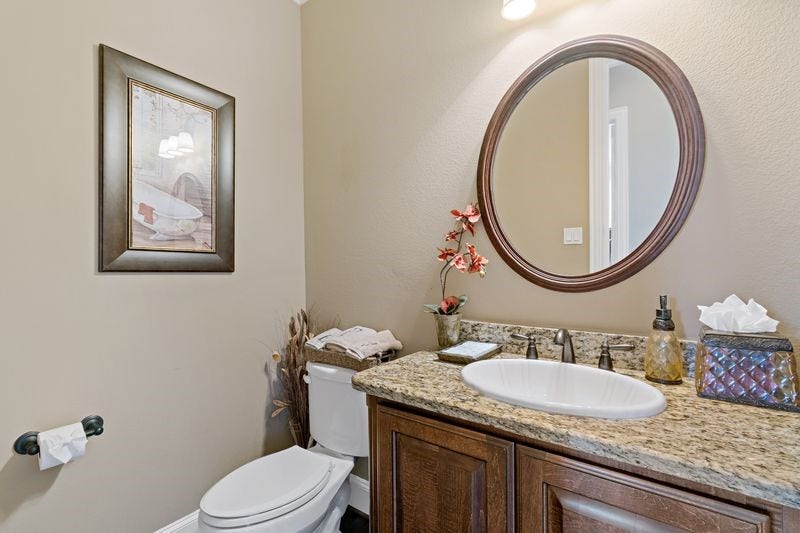 22 Waters Lake Boulevard, Missouri City, TX 77459 Charming powder room featuring a granite countertop, elegant round mirror, and stylish fixtures for a touch of sophistication.