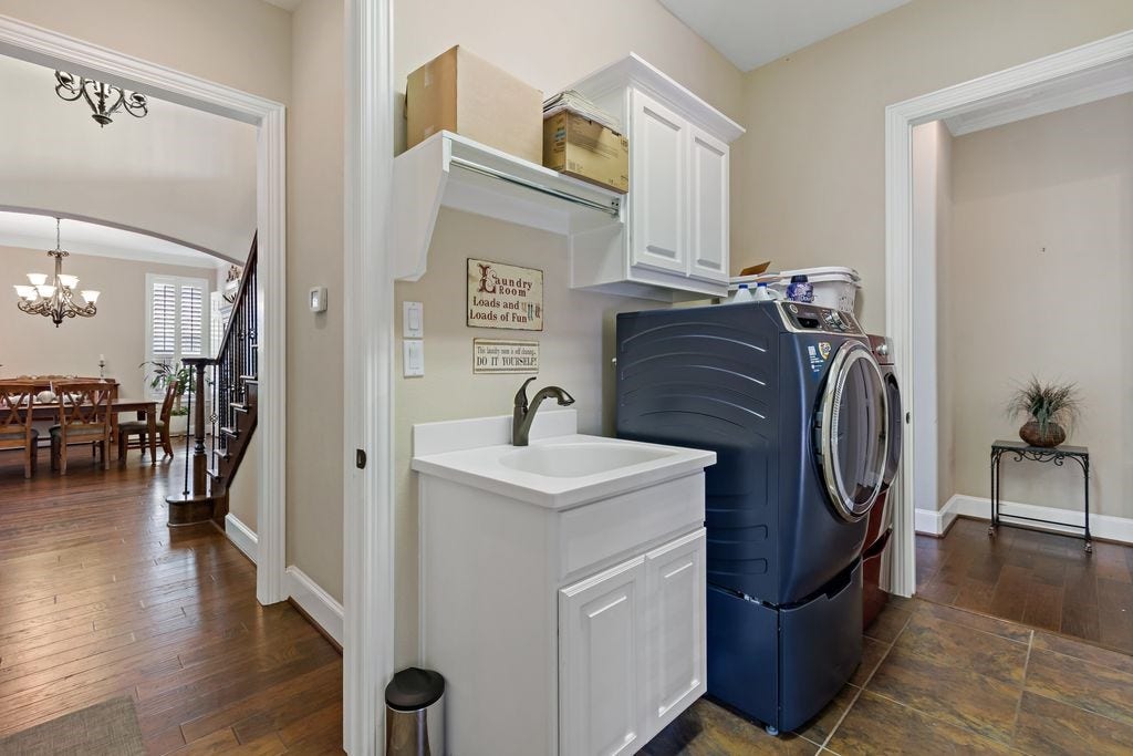 22 Waters Lake Boulevard, Missouri City, TX 77459 Conveniently located near the dining area, this laundry room features modern appliances, ample cabinetry, and a sleek utility sink, offering both functionality and style.