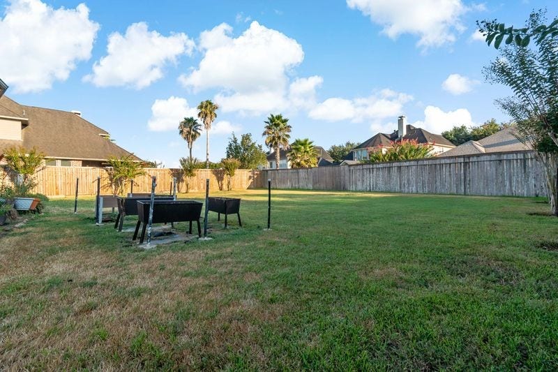 22 Waters Lake Boulevard, Missouri City, TX 77459 Expansive backyard with lush grass, perfect for outdoor activities and gatherings, framed by a private wooden fence and featuring mature trees.