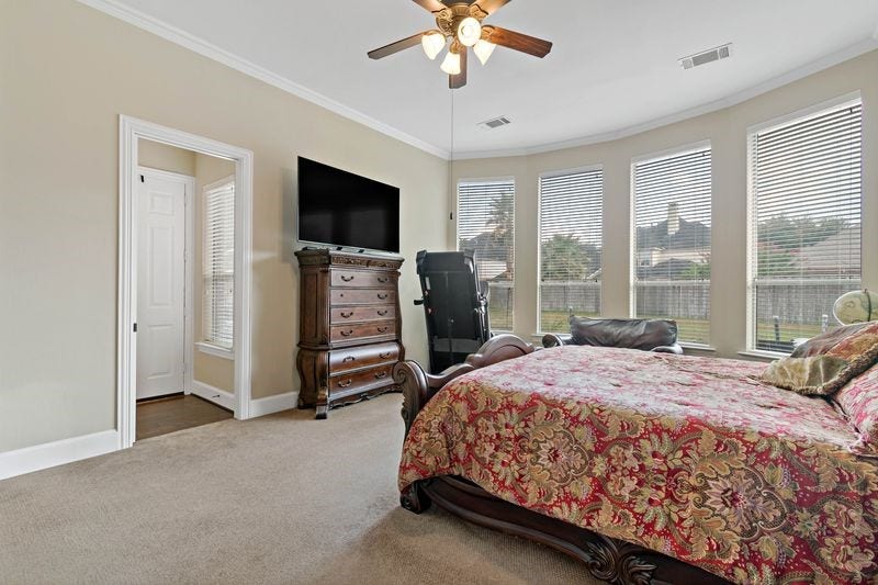 22 Waters Lake Boulevard, Missouri City, TX 77459 Spacious bedroom with large windows offering abundant natural light, elegant furniture, and a ceiling fan for comfort.