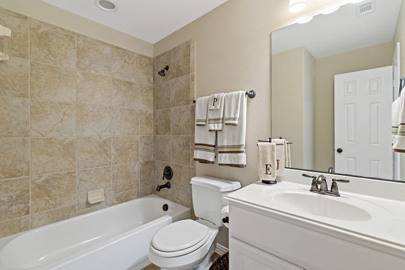 22 Waters Lake Boulevard, Missouri City, TX 77459 Elegant bathroom featuring a tiled shower-bath combo, sleek vanity with ample counter space, and modern fixtures for a polished look.
