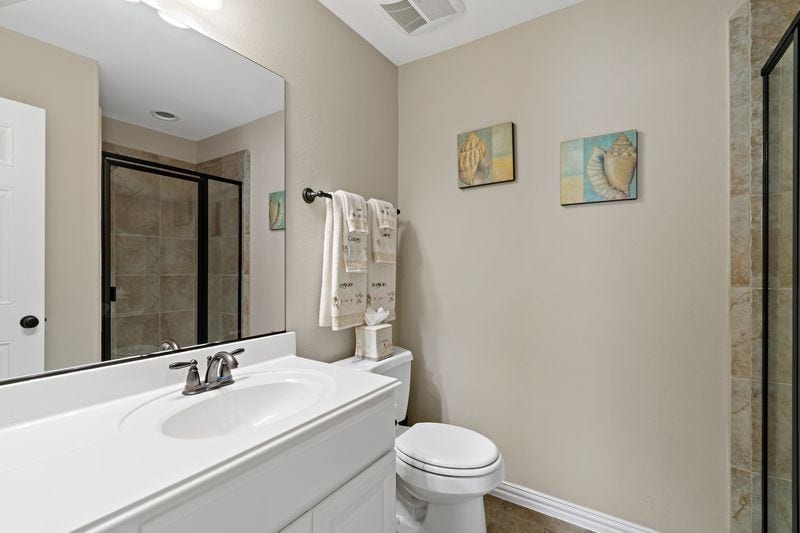 22 Waters Lake Boulevard, Missouri City, TX 77459 Charming bathroom featuring a sleek vanity with a modern faucet, a spacious glass-enclosed shower, and tasteful coastal decor on neutral walls.