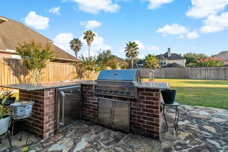 22 Waters Lake Boulevard, Missouri City, TX 77459 Experience outdoor living with this beautifully designed brick outdoor kitchen, featuring a built-in grill and ample counter space, perfect for entertaining in a spacious backyard.