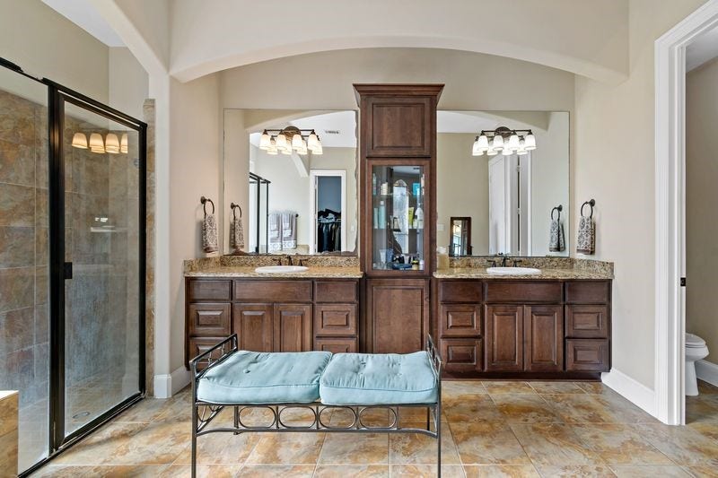 22 Waters Lake Boulevard, Missouri City, TX 77459 Elegant bathroom featuring a double vanity with rich wooden cabinetry, granite countertops, and a spacious glass-enclosed shower.