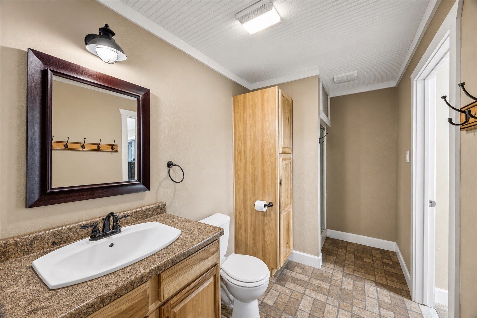 226 S Pine Drive, Montgomery, TX 77356 A wood vanity, rectangular basin, and dark-framed mirror bring warm contrast to the bathroom. A tall cabinet beside the vanity keeps toiletries and linens close at hand.