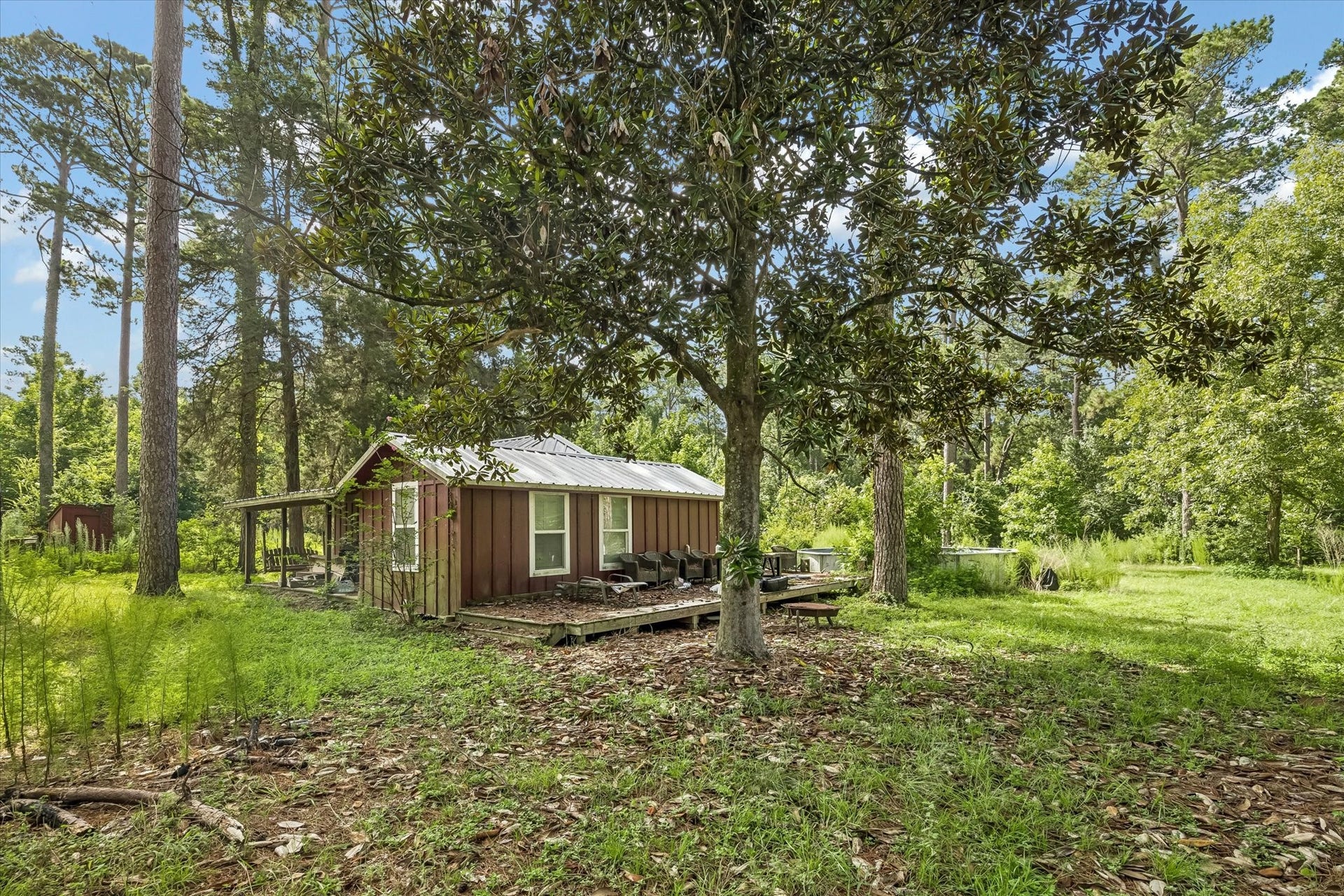 226 S Pine Drive, Montgomery, TX 77356 An additional living space features white-trimmed windows, a metal roof, and a raised wooden porch. Grass and established trees surround this separate building.