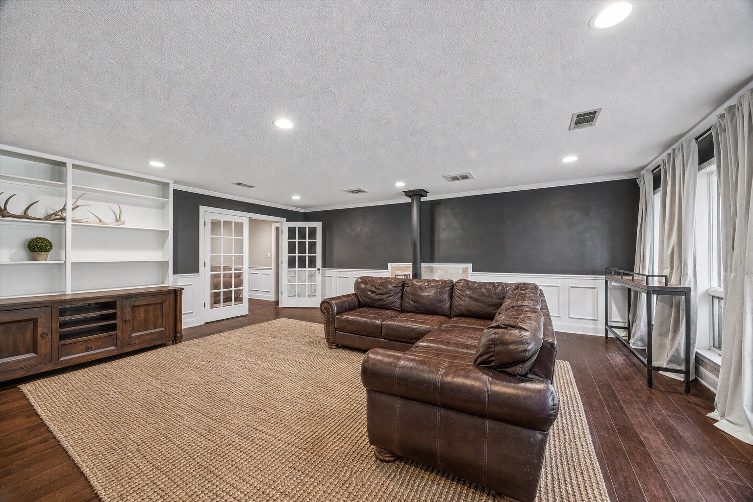 226 S Pine Drive, Montgomery, TX 77356 Charcoal walls and crisp white wainscoting give the living room a distinctive contrast. Built-in shelving and lower cabinetry provide room for books, collected pieces, and media.