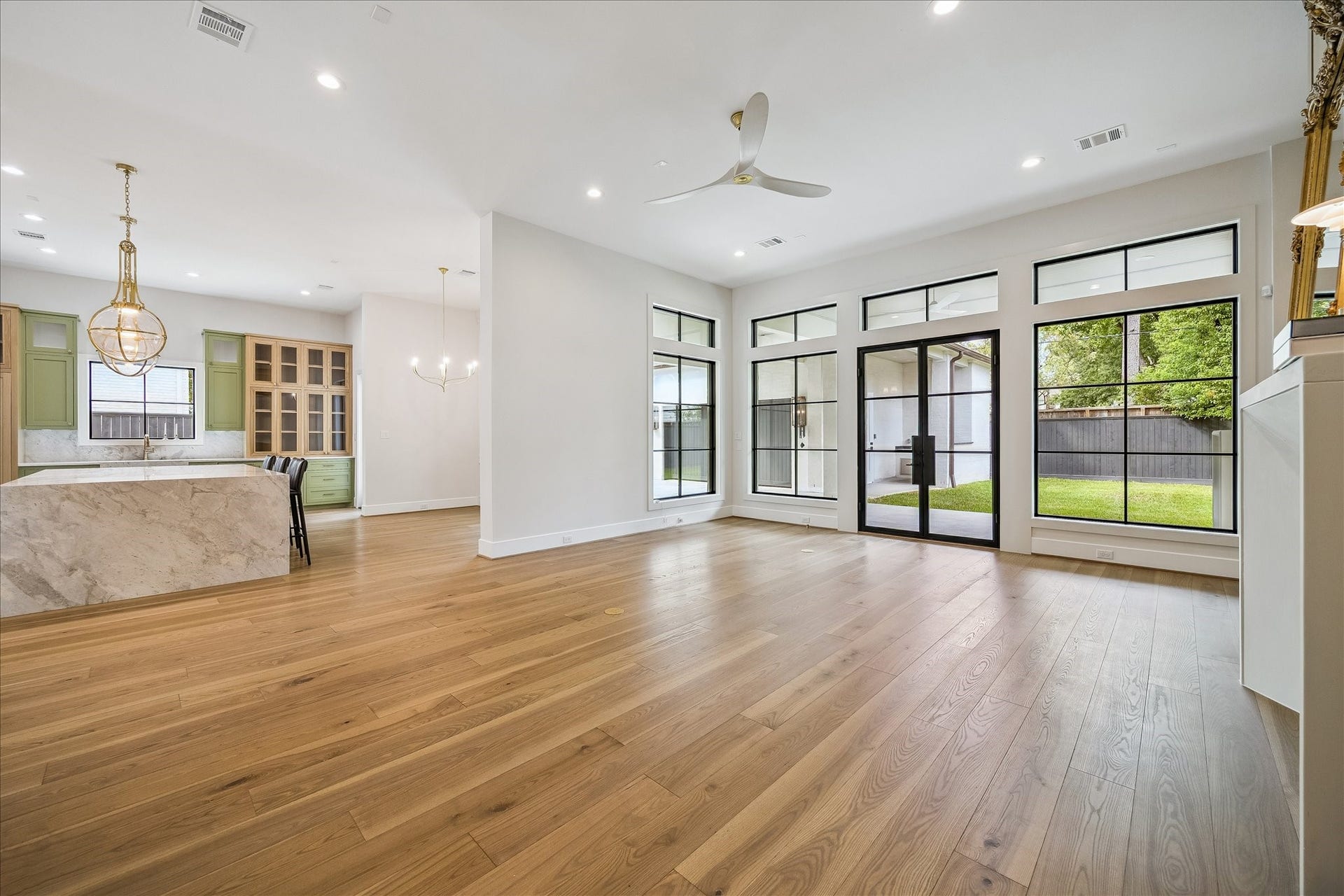 830 Azalea Street, Houston, TX 77018 The living room is a bright and welcoming space, featuring floor-to-ceiling windows that provide stunning views of the backyard. A gas fireplace with a white oak surround adds warmth and elegance to the room. Steel-framed doors open to a covered patio, seamlessly connecting the indoor and outdoor living areas, enhancing the versatility and enjoyment of the space.