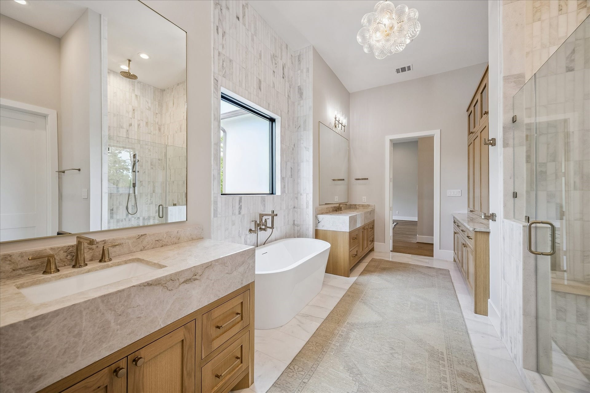830 Azalea Street, Houston, TX 77018 The primary retreat boasts ceilings that create an expansive and airy feel. The bathroom is beautifully appointed with Taj Mahal quartzite separate vanities, a freestanding acrylic soaking tub, and an oversized glass-enclosed shower featuring dual fixtures.