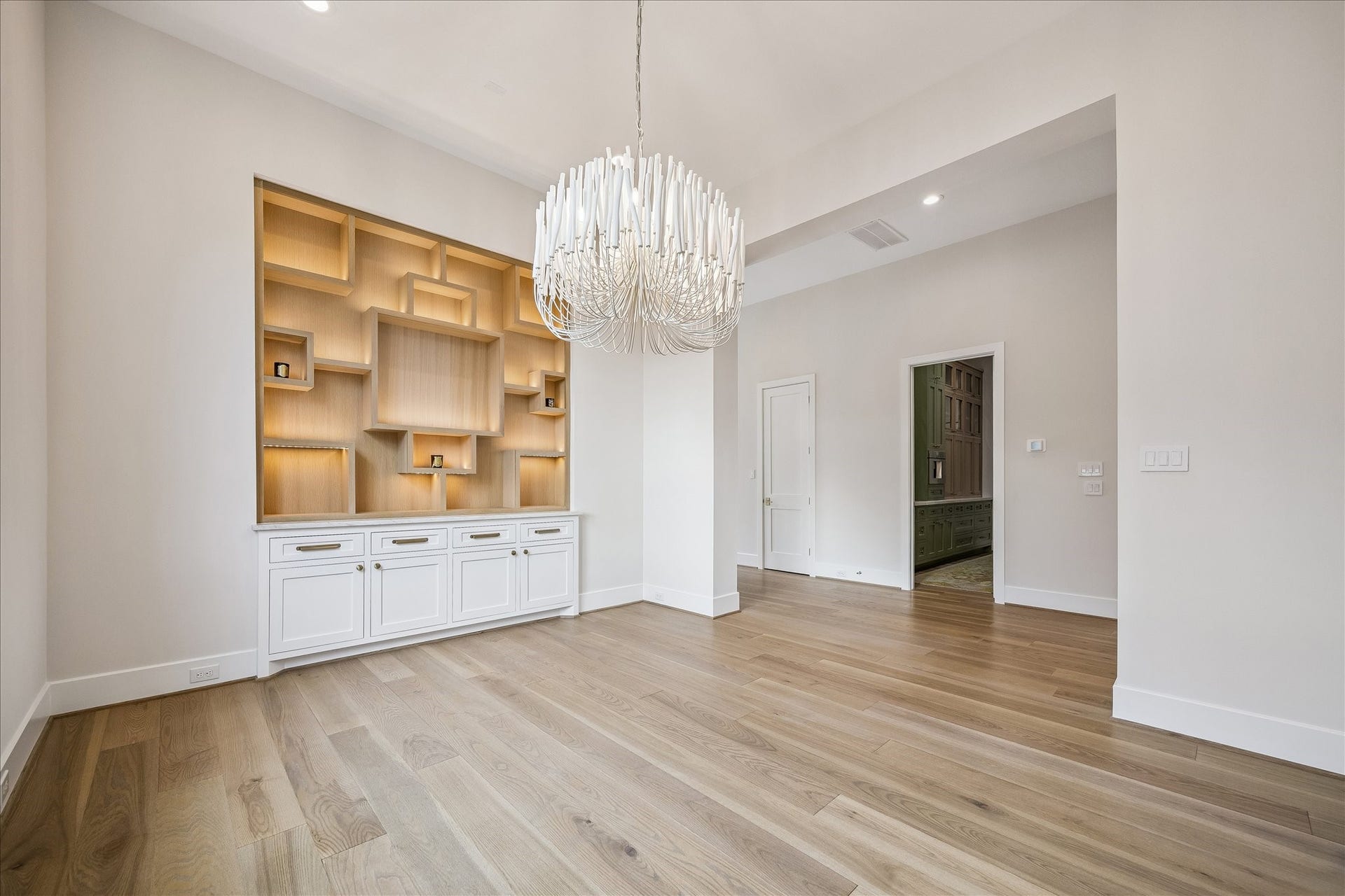 830 Azalea Street, Houston, TX 77018 Forma Dining area features white oak cabinetry with integrated display shelving. Designer chandelier providing warm architectural presence.