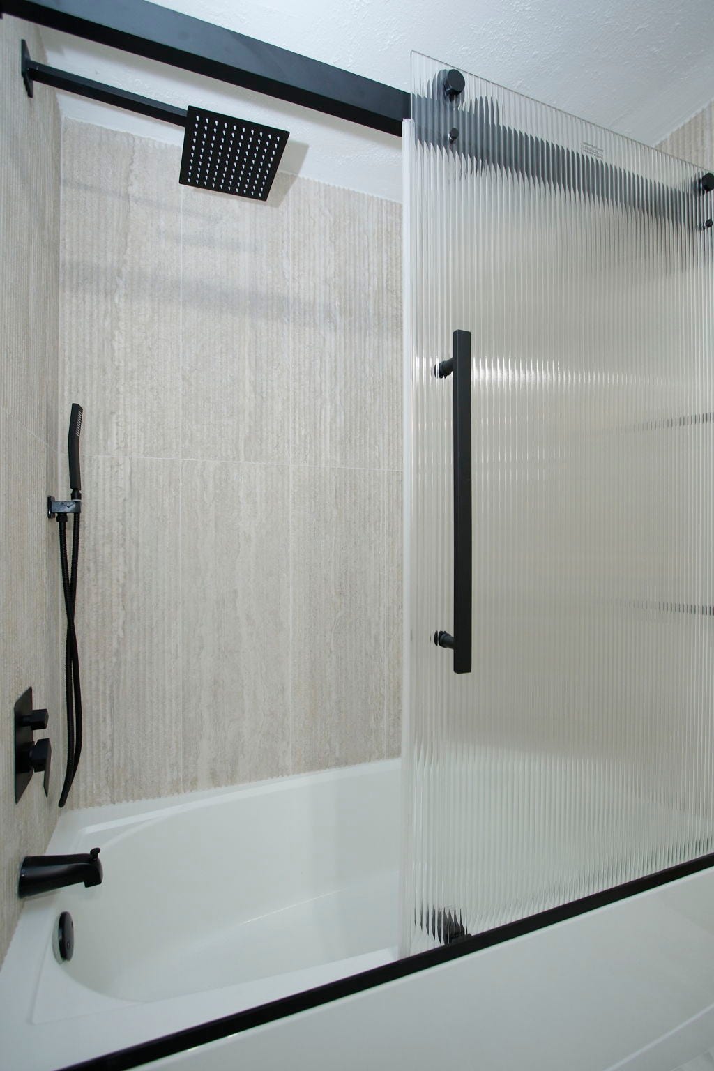 207 Burgundy Lane, League City, TX 77573 Main bathroom's shower / tub combo, with wooden like walls, rainfall showerhead and contrastind fixtures.