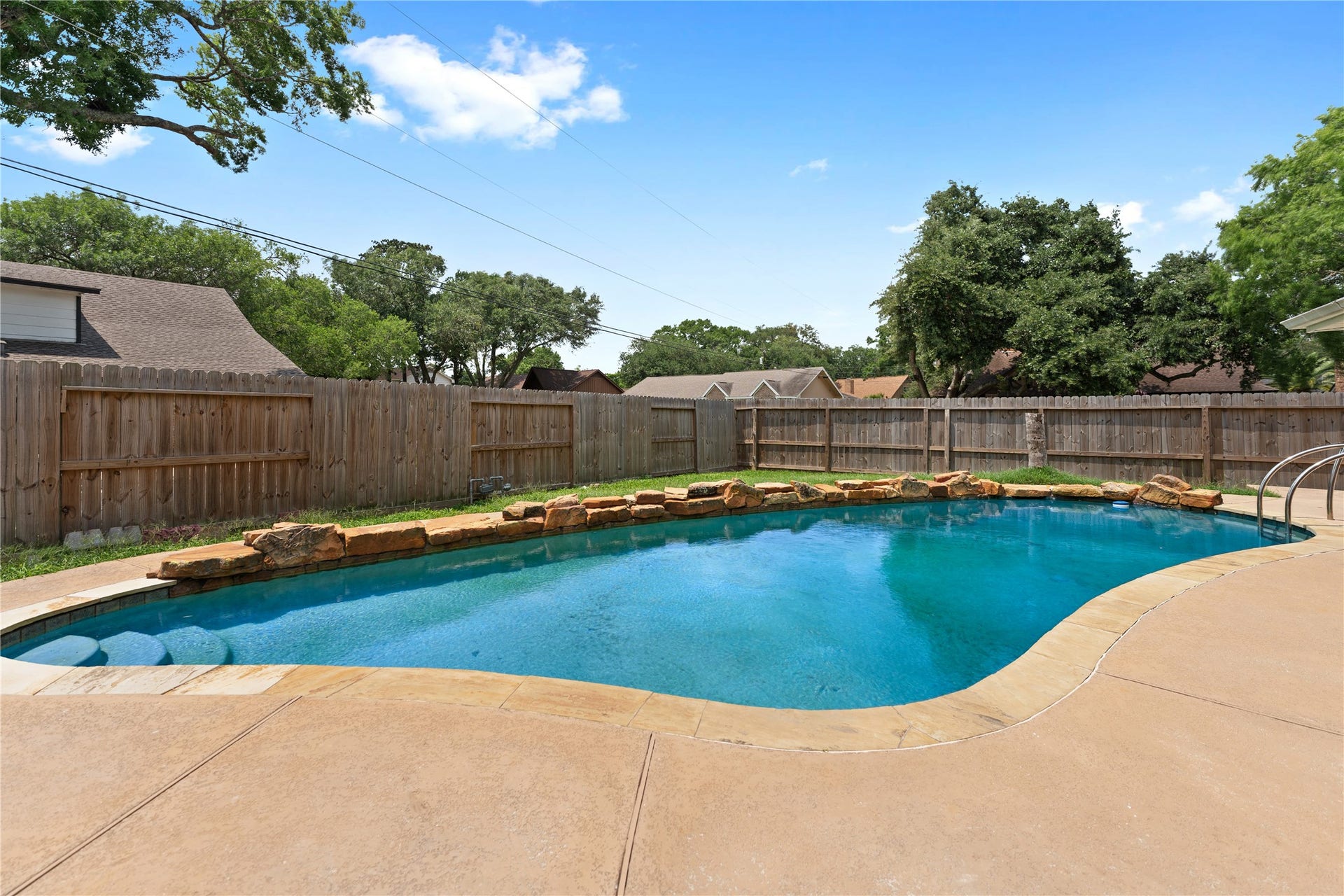 207 Burgundy Lane, League City, TX 77573 The in-ground swimming pool is bordered by natural stone accents and a spacious concrete patio, offering a relaxing outdoor space.