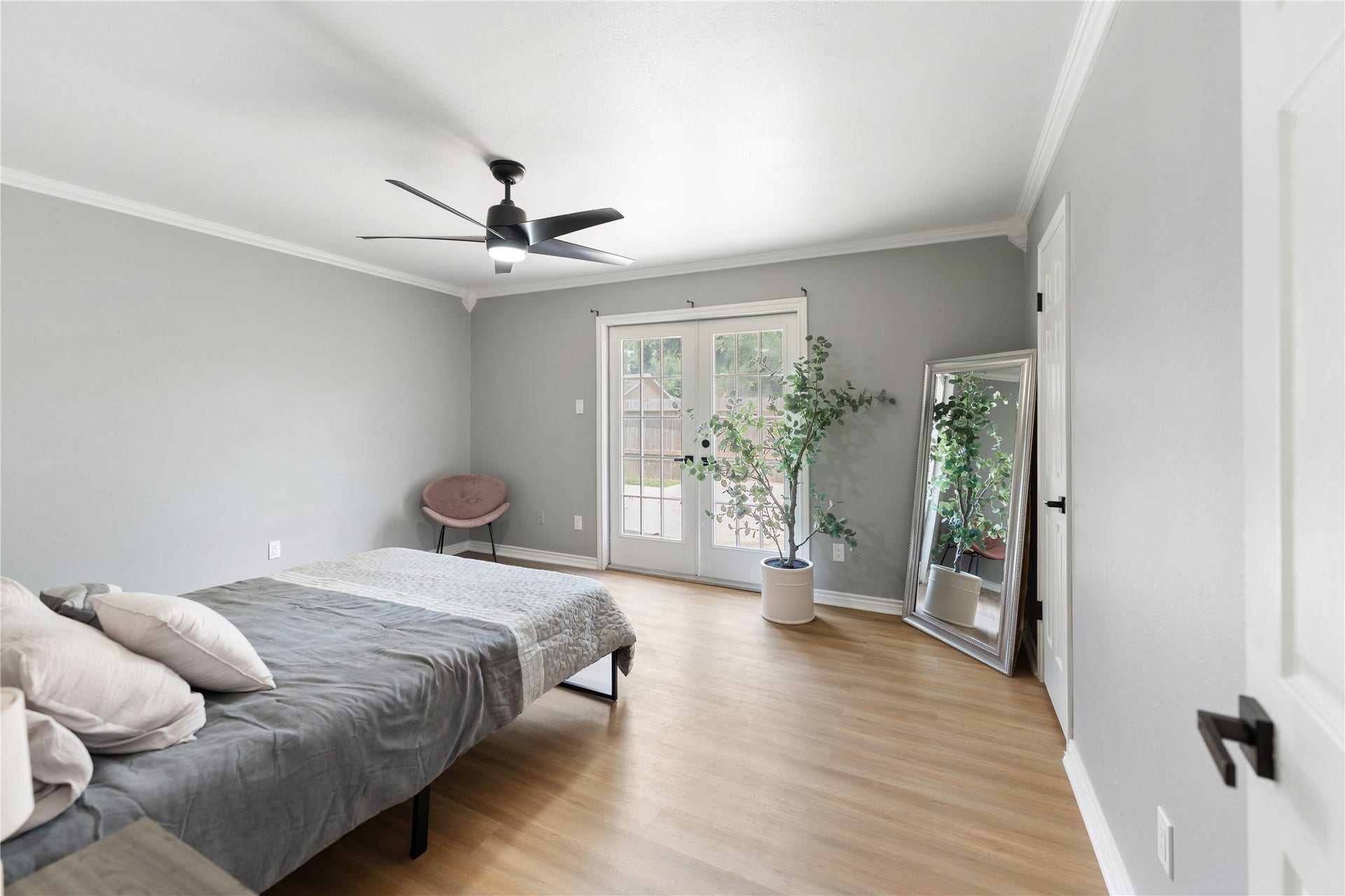 207 Burgundy Lane, League City, TX 77573 The spacious main bedroom features a modern ceiling fan, soft color palette, and hardwood floors. The elegant french door bring lots of sunshine making this an inviting room