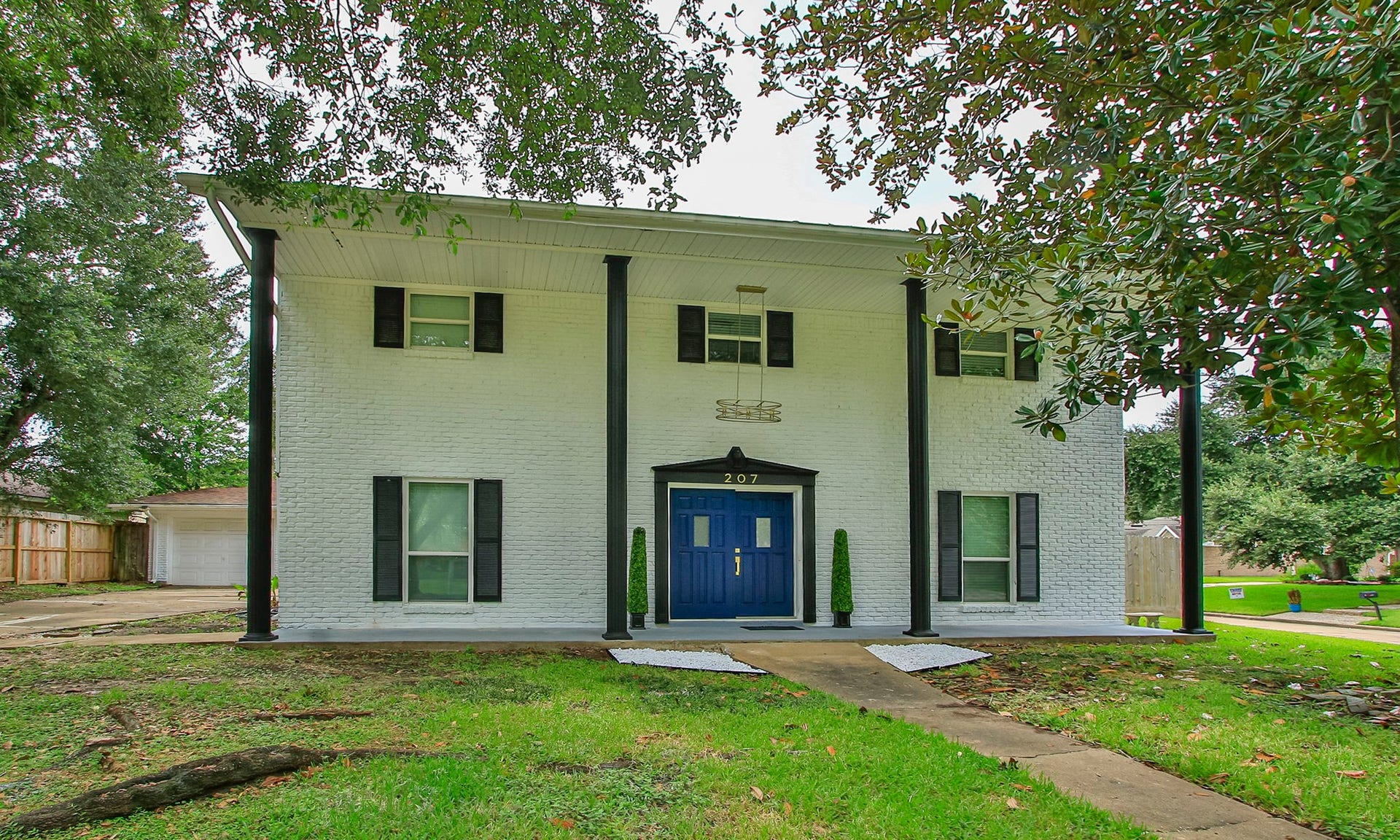 207 Burgundy Lane, League City, TX 77573 The bright facade, with contrasting colums and shutters and an elegant golden light fixture