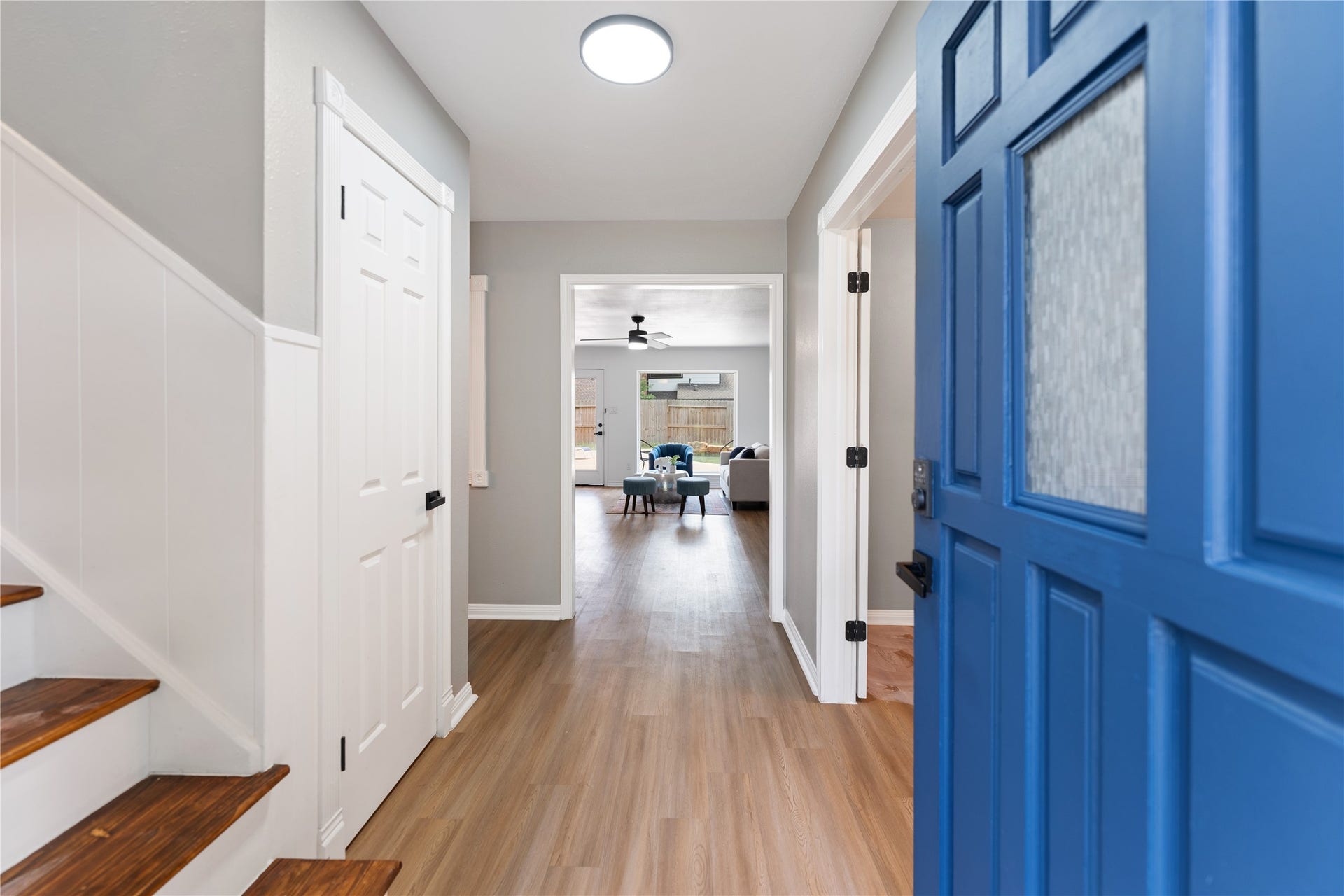 207 Burgundy Lane, League City, TX 77573 Welcome to the bright entryway, featuring a vibrant blue door, sleek wood flooring, and neutral walls leading to the inviting living area