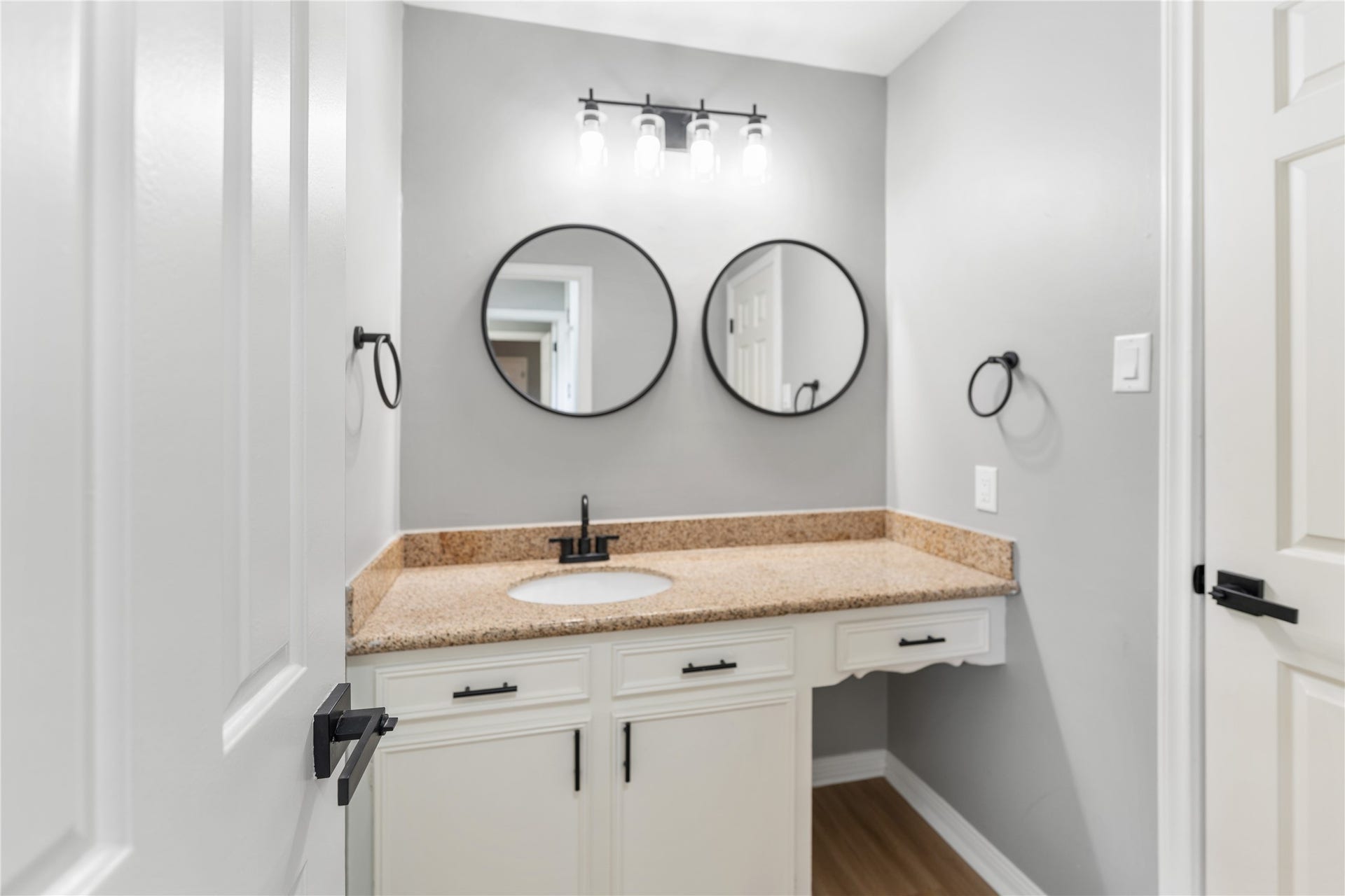 207 Burgundy Lane, League City, TX 77573 The secondary Jack and Jill style bathroom features a modern vanity with a granite countertop, dual round mirrors, and stylish lighting. The neutral color palette and sleek fixtures create a clean, contemporary look.