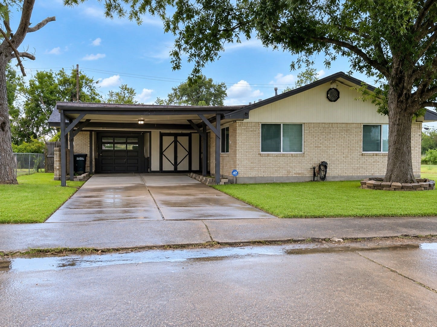 514 Idlewood Drive, Hitchcock, TX 77563 Front Exterior: Welcoming exterior view showcasing the home's classic brick faade, mature shade tree, spacious lawn, and covered parking.