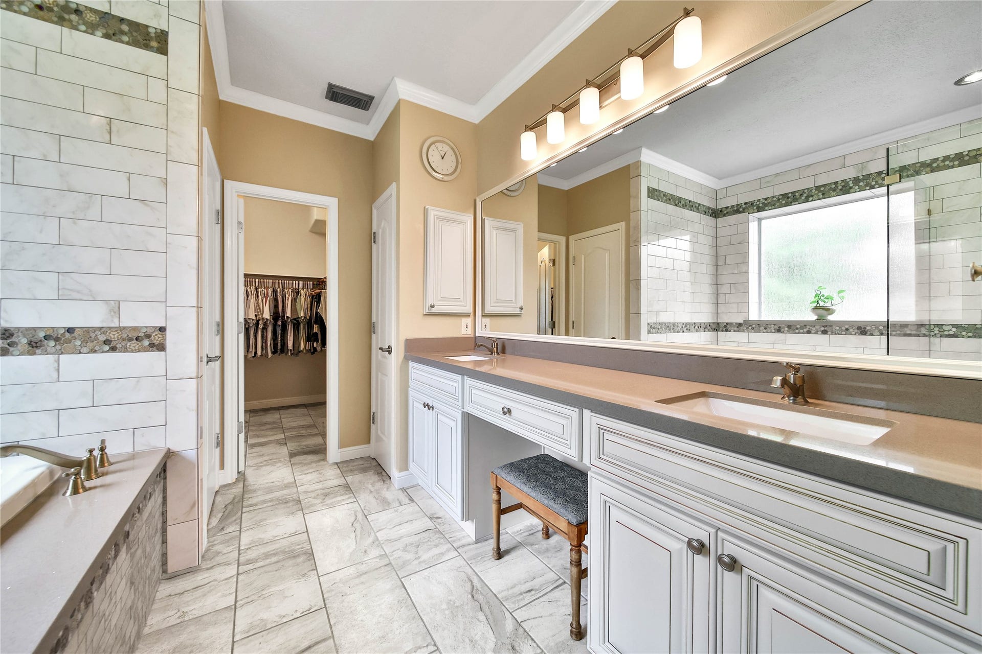 Two linen closets, vanity, double sinks, oversize shower, designer finishes, custom cabinetry, and framed mirror make this incredible primary bathroom ensuite stand out. HUGE connected closet and dressing room!