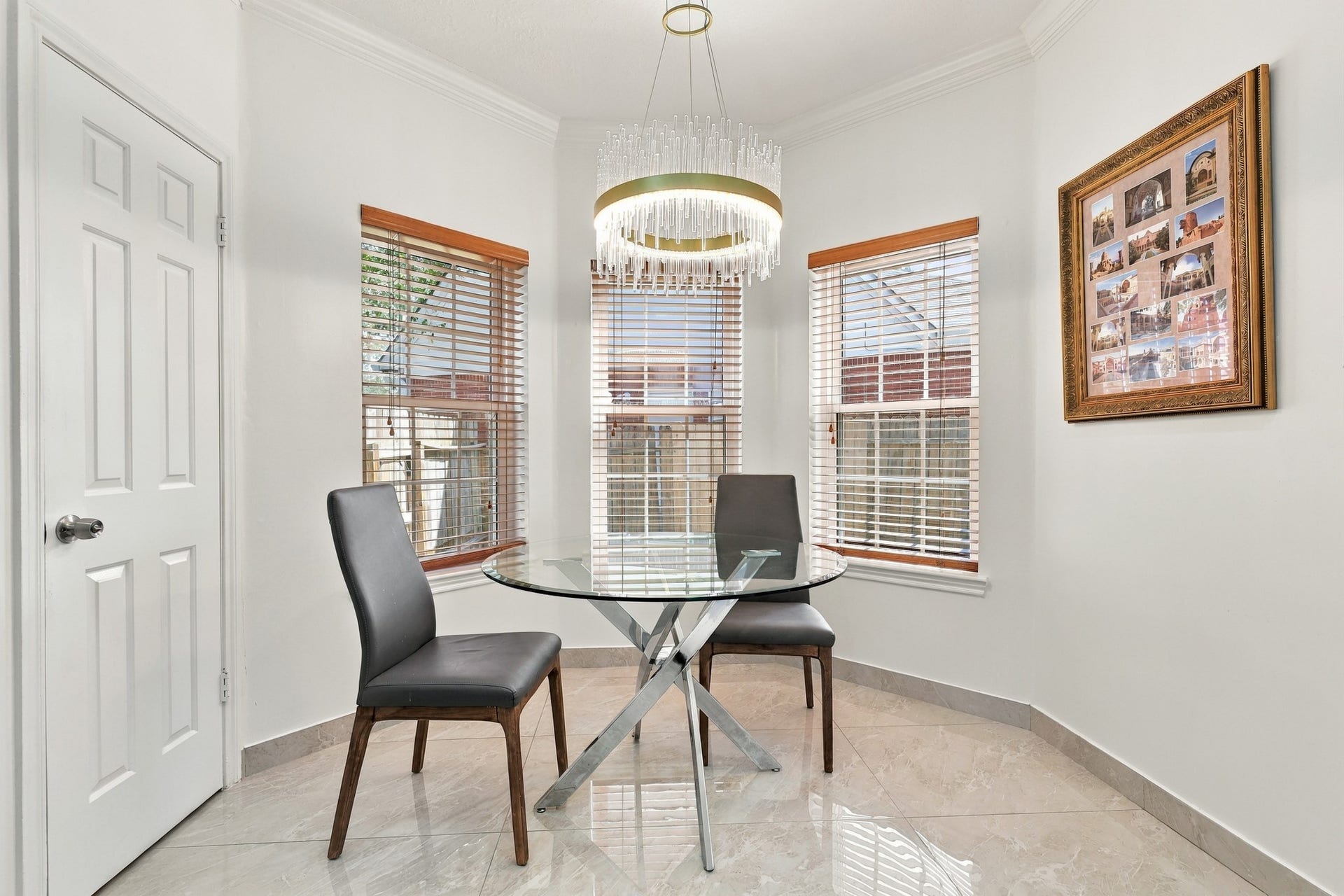 14538 Circlewood Way, Houston, TX 77062 Charming breakfast nook featuring a curved bay of three windows that fills the space with natural light. An elegant crystal-style chandelier with gold accents adds a sophisticated touch, while crown molding, wood-trimmed blinds, and polished marble tile flooring complete this inviting dining space.