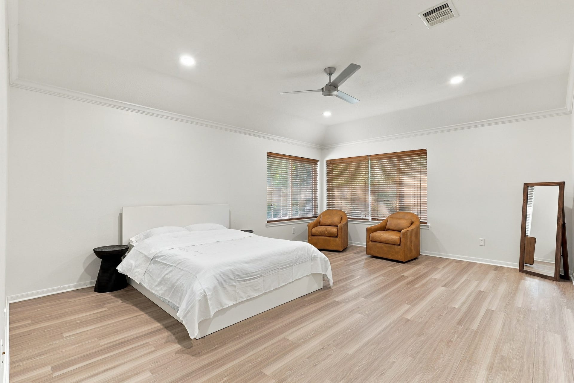14538 Circlewood Way, Houston, TX 77062 Expansive primary suite featuring beautiful wood flooring, crown molding, recessed lighting, and a modern ceiling fan. Two large windows fill the room with natural light, while the generous layout easily accommodates a sitting area or additional furnishings.