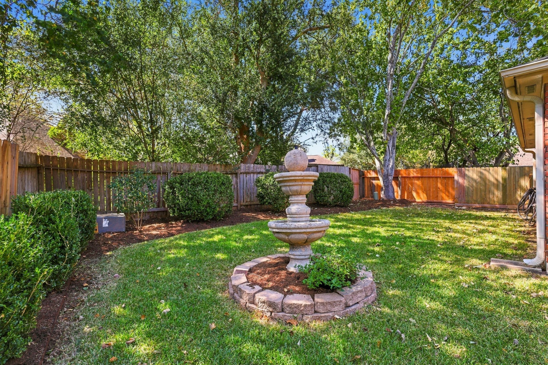 14538 Circlewood Way, Houston, TX 77062 The backyard offers a peaceful, private-feeling retreat surrounded by mature shade trees, established landscaping, and wood fencing. A decorative tiered fountain serves as the centerpiece of the lawn, complemented by neatly maintained shrubs and plenty of green space for outdoor enjoyment.