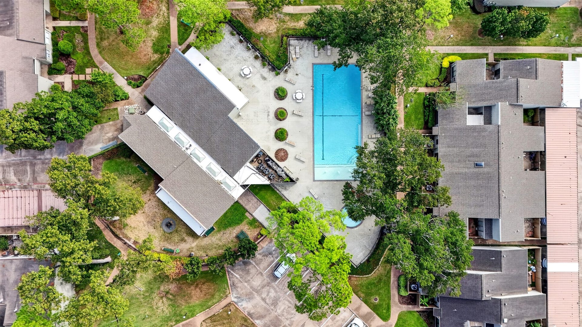 2379 Briarwest Boulevard, #85, Houston, TX 77077 Top-down aerial of the community pool and clubhouse deck, lined with loungers and shaded by oaks.