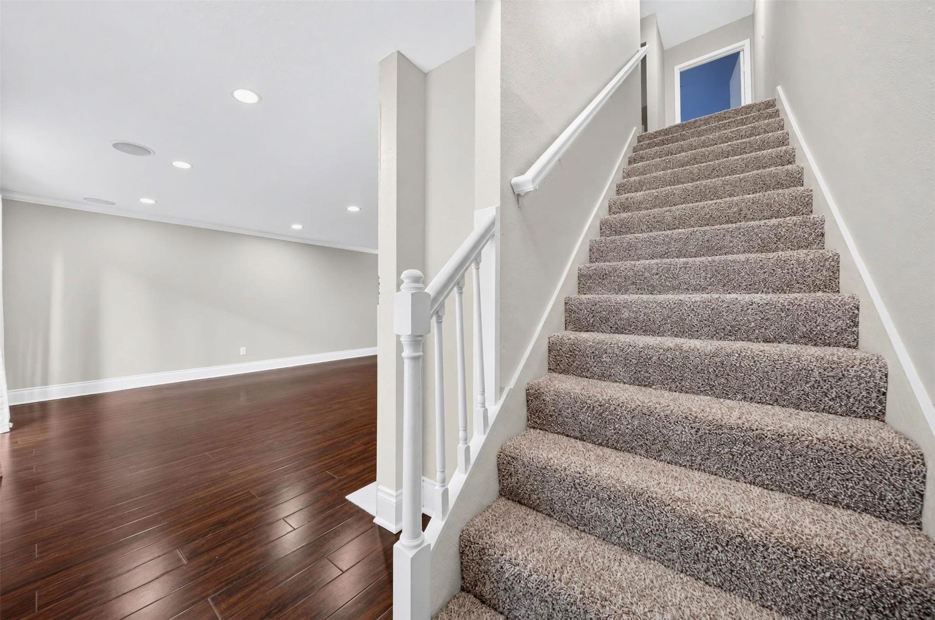 2379 Briarwest Boulevard, #85, Houston, TX 77077 Carpeted stairs with a white wood railing climb from the main level, where dark hardwoods and recessed lights continue into the living area.