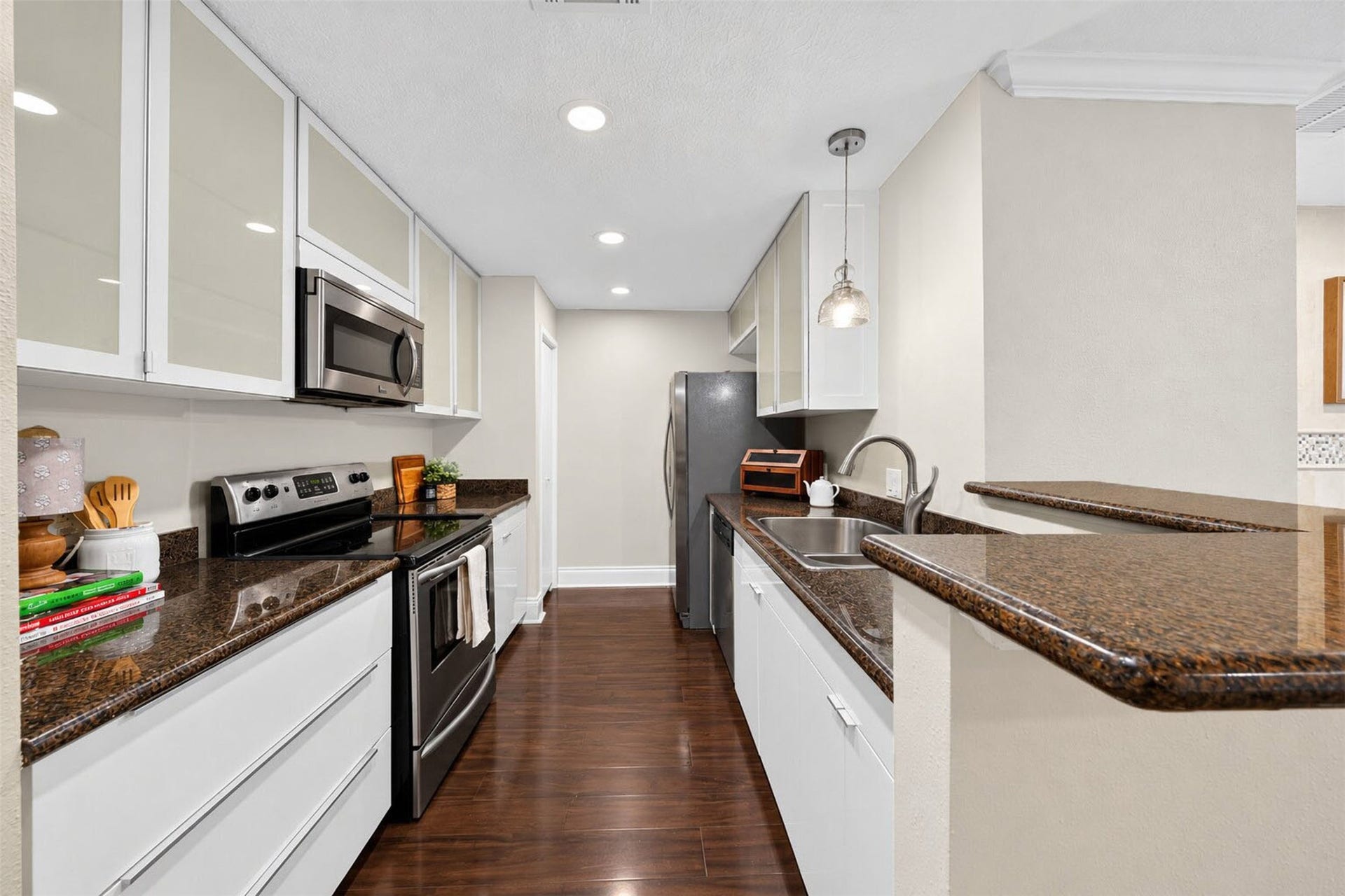 2379 Briarwest Boulevard, #85, Houston, TX 77077 The galley kitchen pairs glossy white cabinetry with dark granite counters and stainless appliances smooth-top range, built-in microwave, and French-door fridge. A double sink and raised breakfast bar open to the dining room.