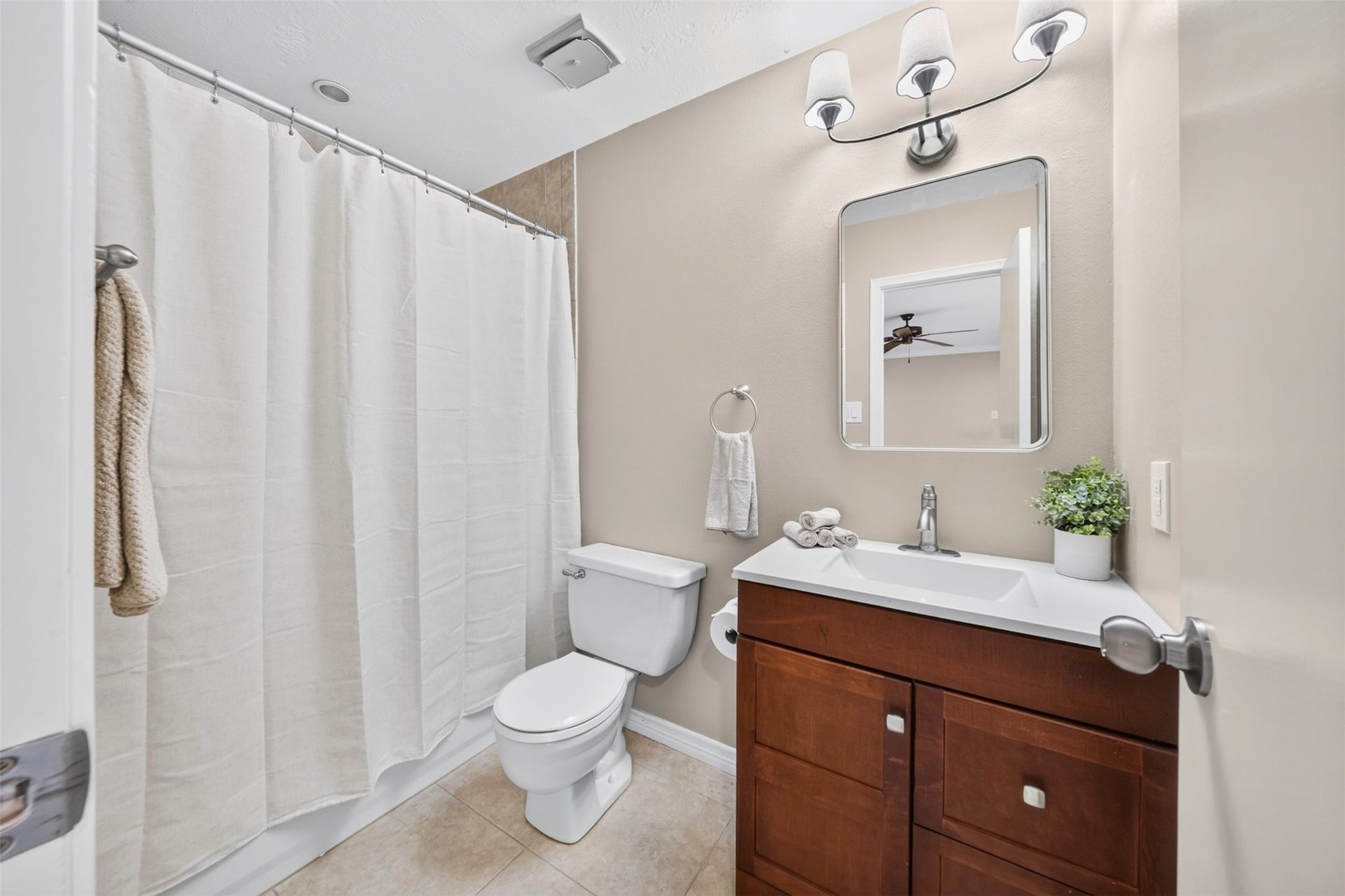 2379 Briarwest Boulevard, #85, Houston, TX 77077 This full bath pairs a rich dark-wood vanity with a white countertop sink, a rounded mirror, and a tub/shower with a linen curtain.
