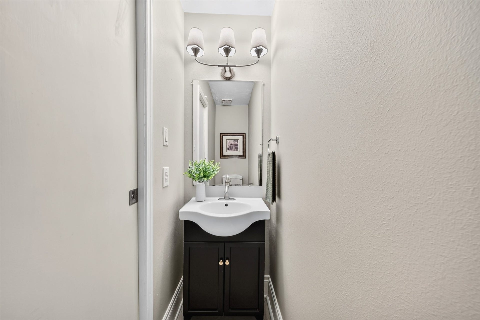 2379 Briarwest Boulevard, #85, Houston, TX 77077 A tidy main-floor powder room with a dark vanity cabinet, scalloped white sink, mirrored medicine cabinet, and a three-light fixture convenient for guests.