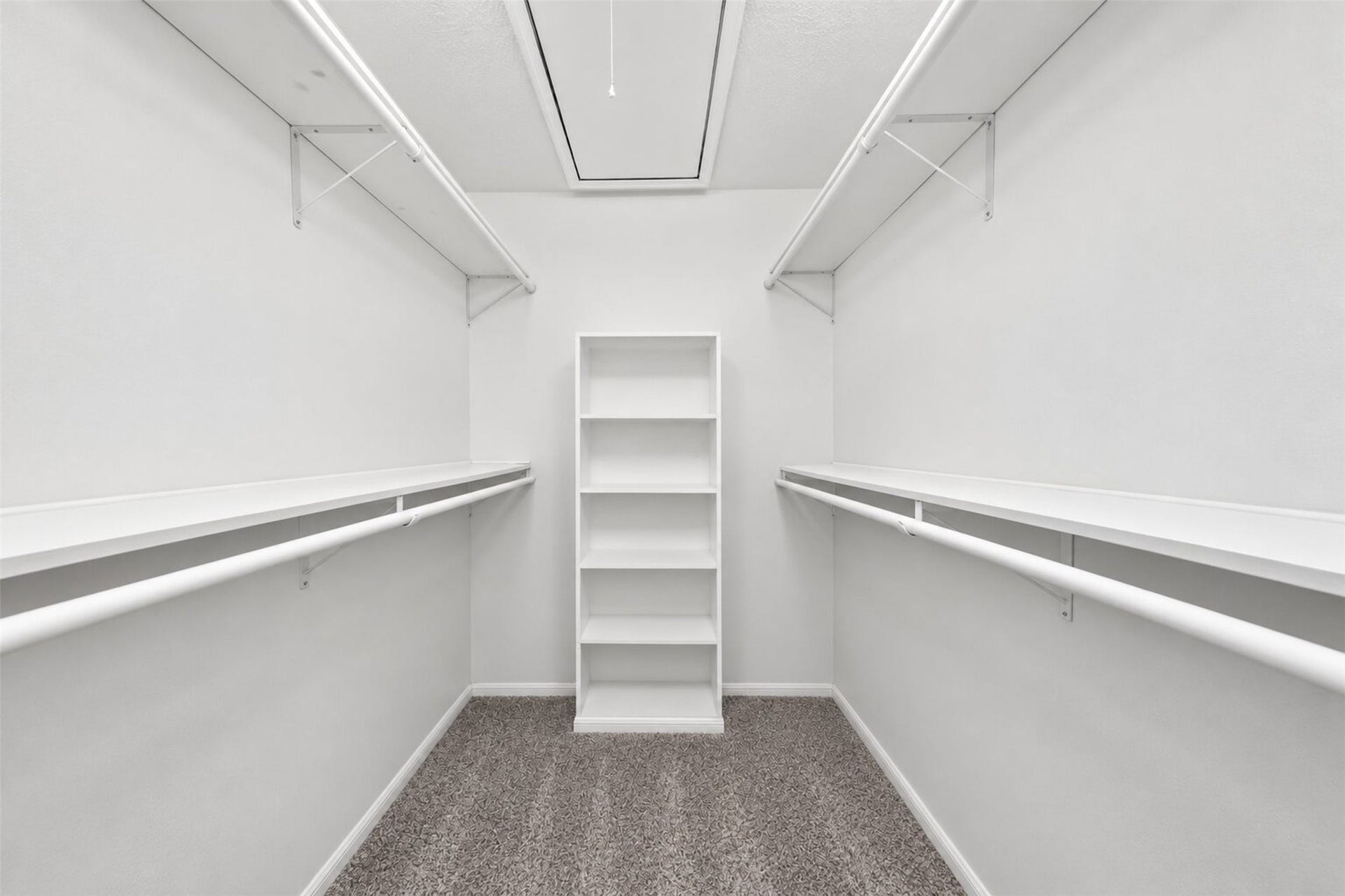 2379 Briarwest Boulevard, #85, Houston, TX 77077 The primary walk-in closet is lined with double hanging rods and shelving on both sides, plus a built-in shelving tower and attic access above.