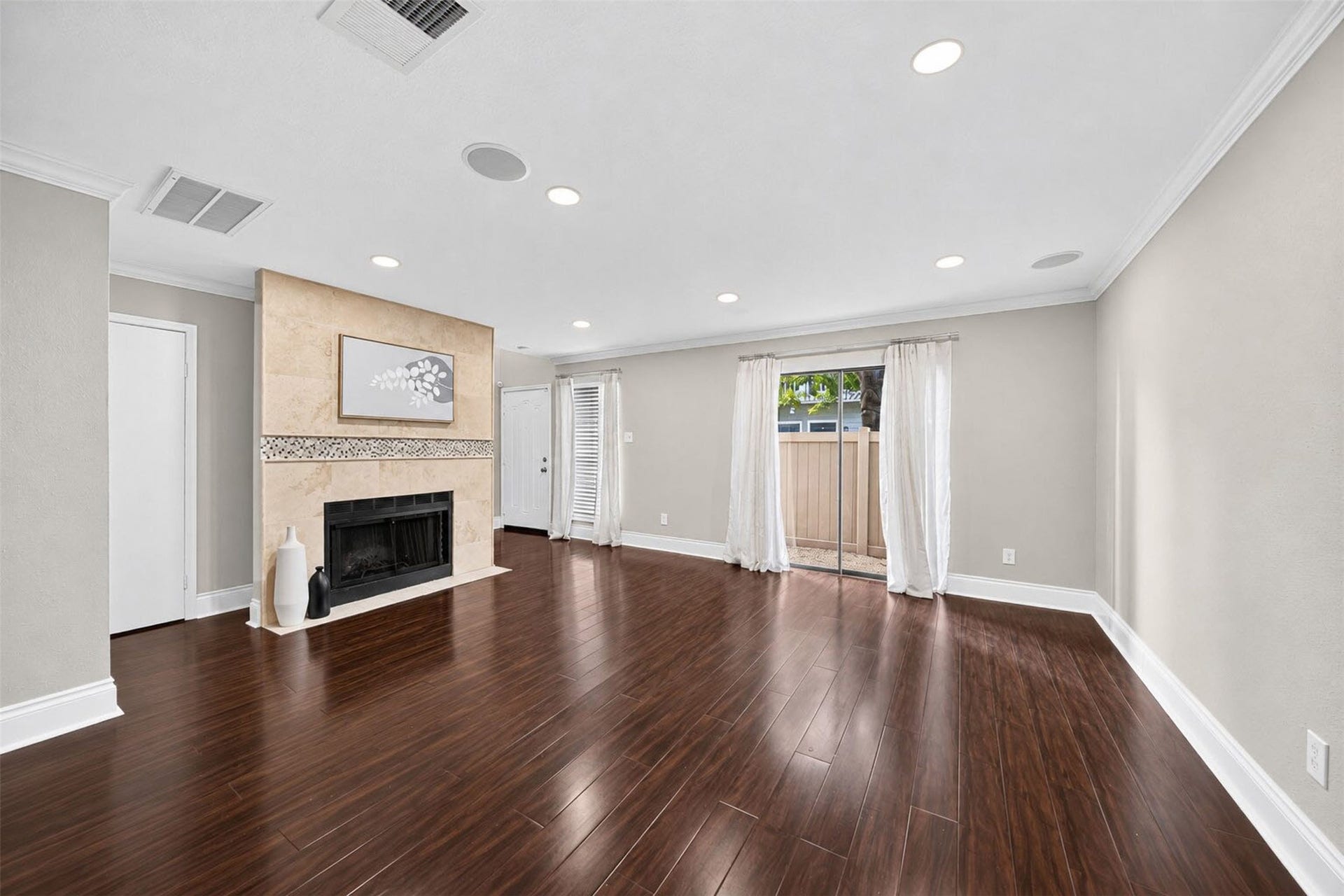 2379 Briarwest Boulevard, #85, Houston, TX 77077 From the dining side, the living room centers on the tiled fireplace, with the front door beyond and a sliding glass door opening to the side patio. Dark wood floors and in-ceiling speakers run throughout.