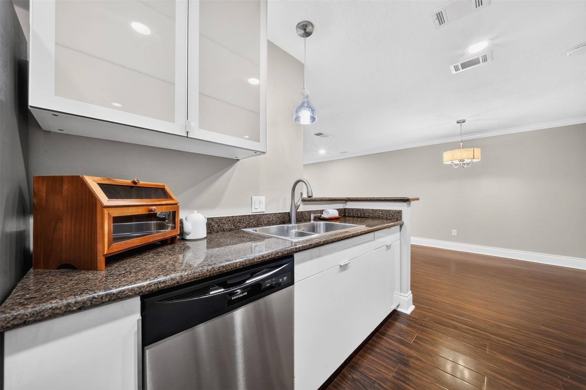 2379 Briarwest Boulevard, #85, Houston, TX 77077 Along the sink counter: a stainless double sink, dishwasher, and a pendant light above, with the dining room and its chandelier open beyond the breakfast bar.