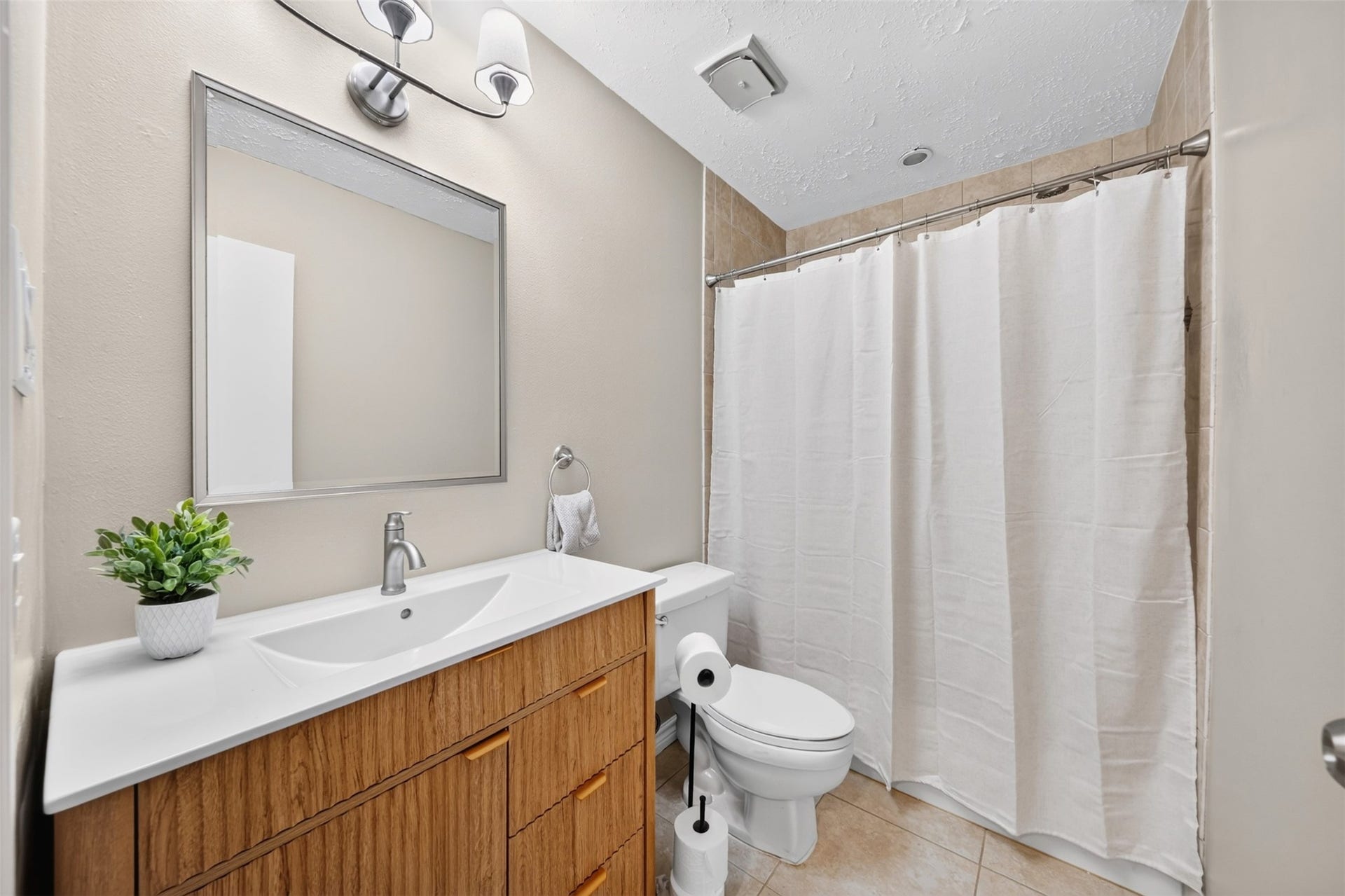 2379 Briarwest Boulevard, #85, Houston, TX 77077 The primary bath features a wood-front vanity with an integrated sink, a large framed mirror, and a tub/shower combo with tile surround. Tile floors and brushed-nickel fixtures.