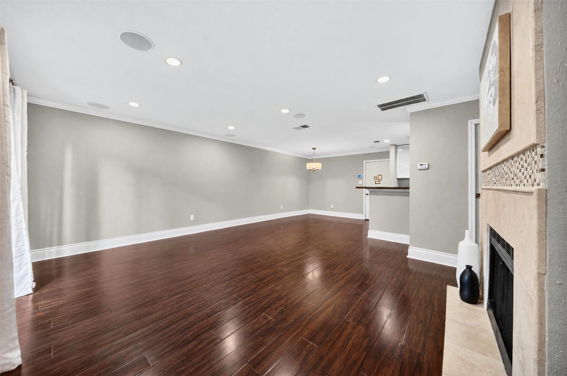 2379 Briarwest Boulevard, #85, Houston, TX 77077 Looking down the length of the open living space toward the dining area and kitchen bar, with the fireplace hearth at right. Gleaming dark hardwoods and recessed lighting throughout.