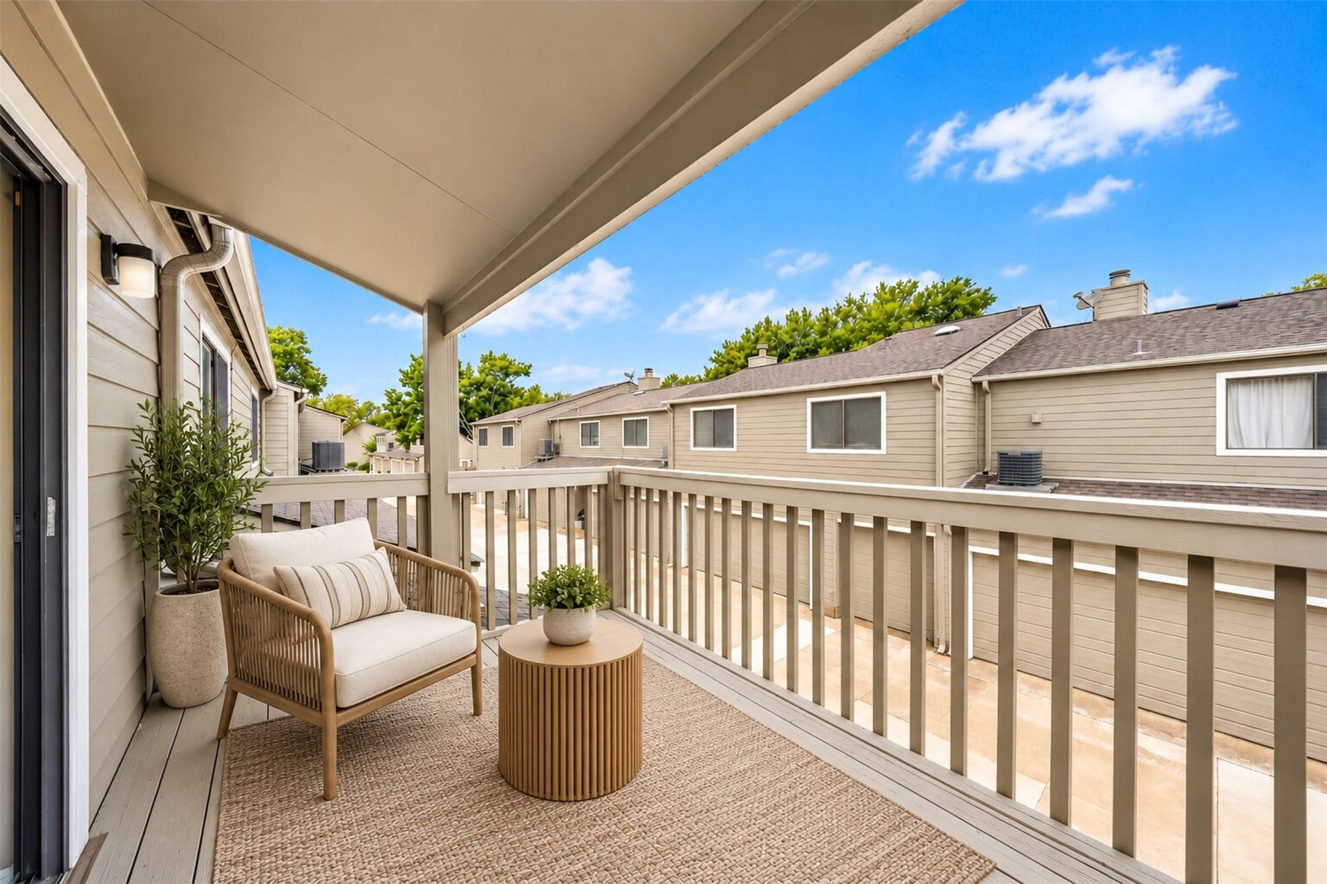 2379 Briarwest Boulevard, #85, Houston, TX 77077 Virtually staged with a woven lounge chair and side table, the covered upstairs balcony becomes a private perch for morning coffee, overlooking the quiet community below.